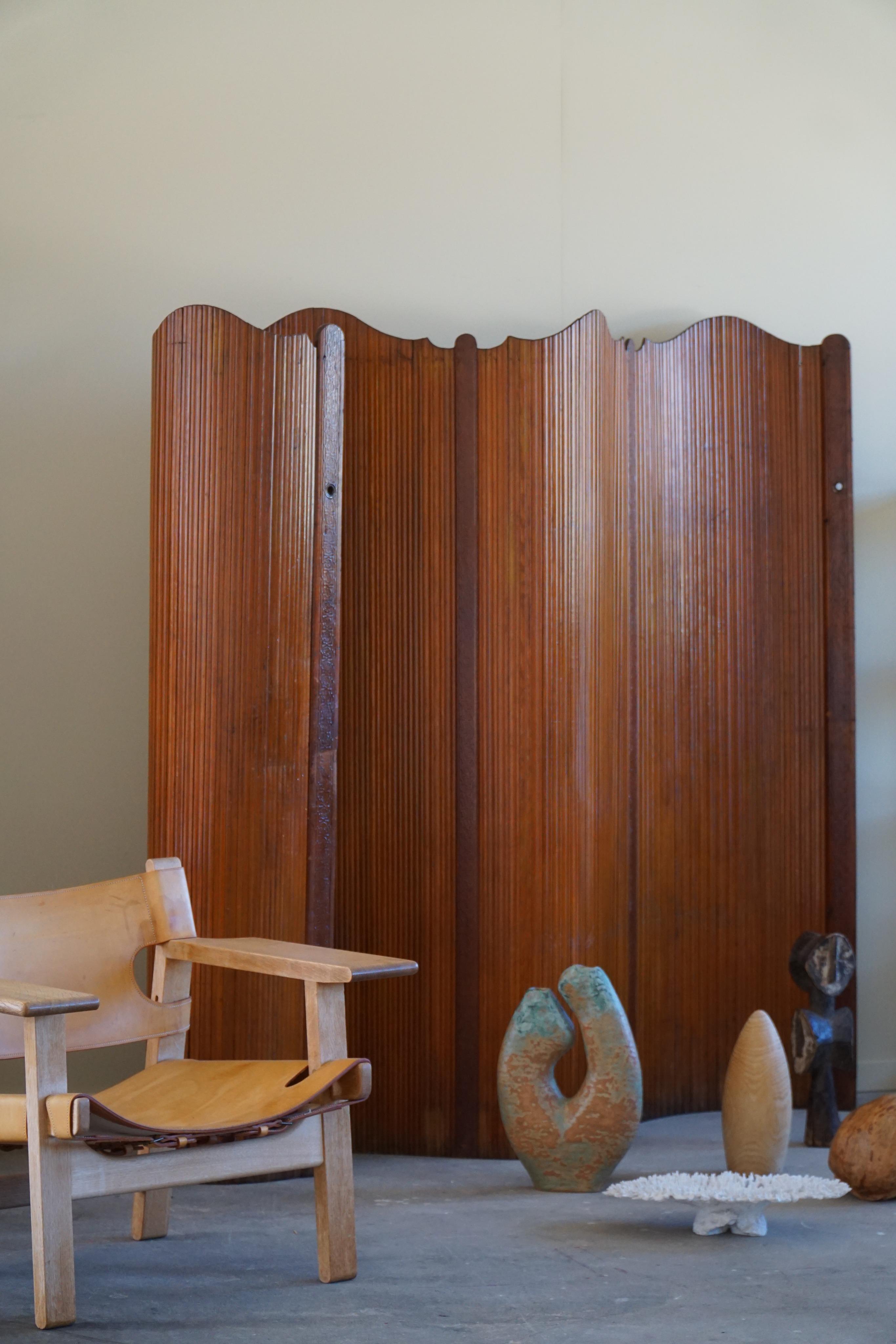 This Art Deco room divider is a masterpiece of design and craftsmanship, standing tall and commanding attention with its sleek and streamlined form. The patinated pine wood is rich in color, with deep brown tones that provide a warm and inviting