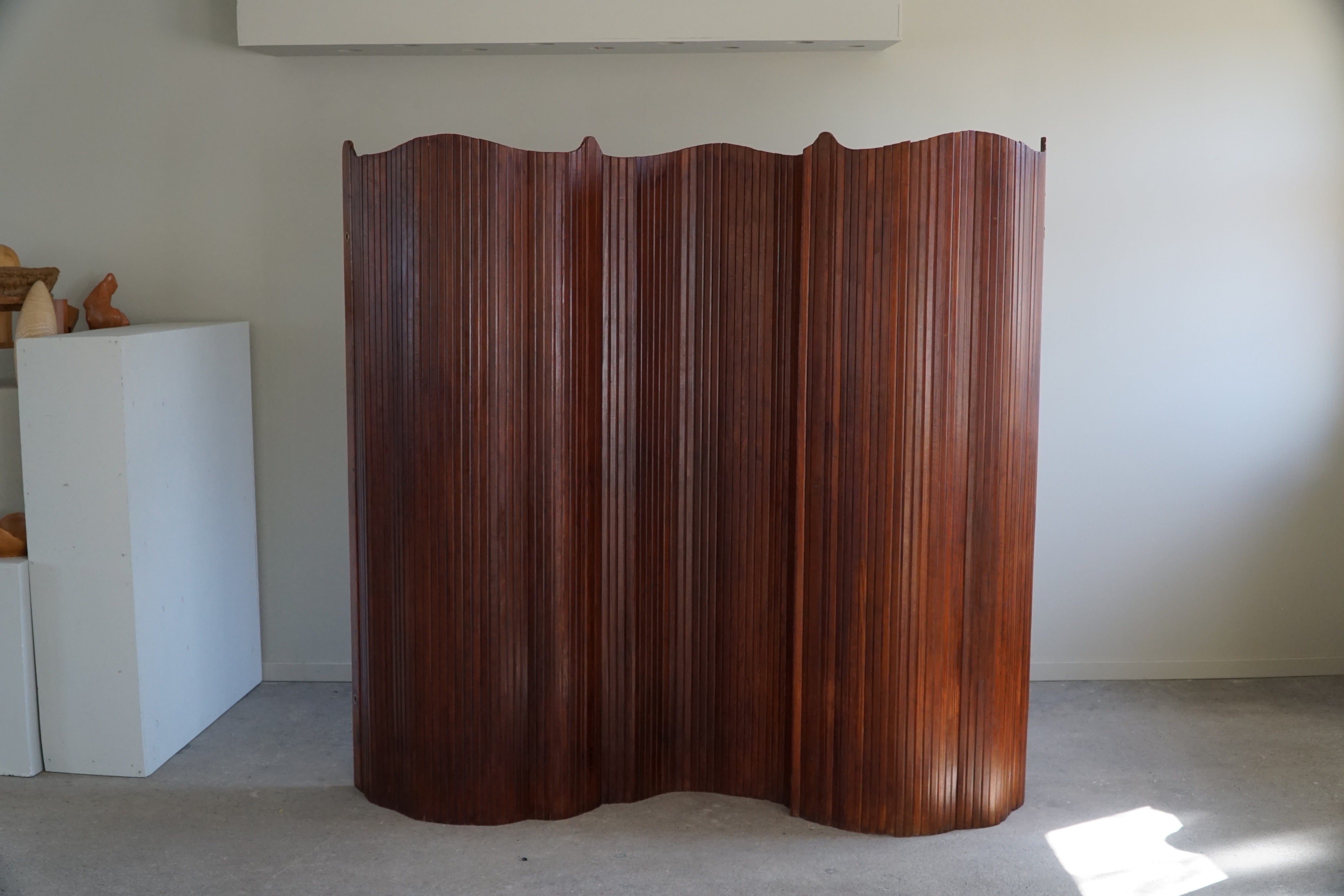 This French Art Deco tambour room divider is a stunning piece of furniture attributed to the French cabinetmaker Jomaine Baumann and made in the 1930s. Crafted in pine, the tambour panels are intricately woven to create a flexible, undulating