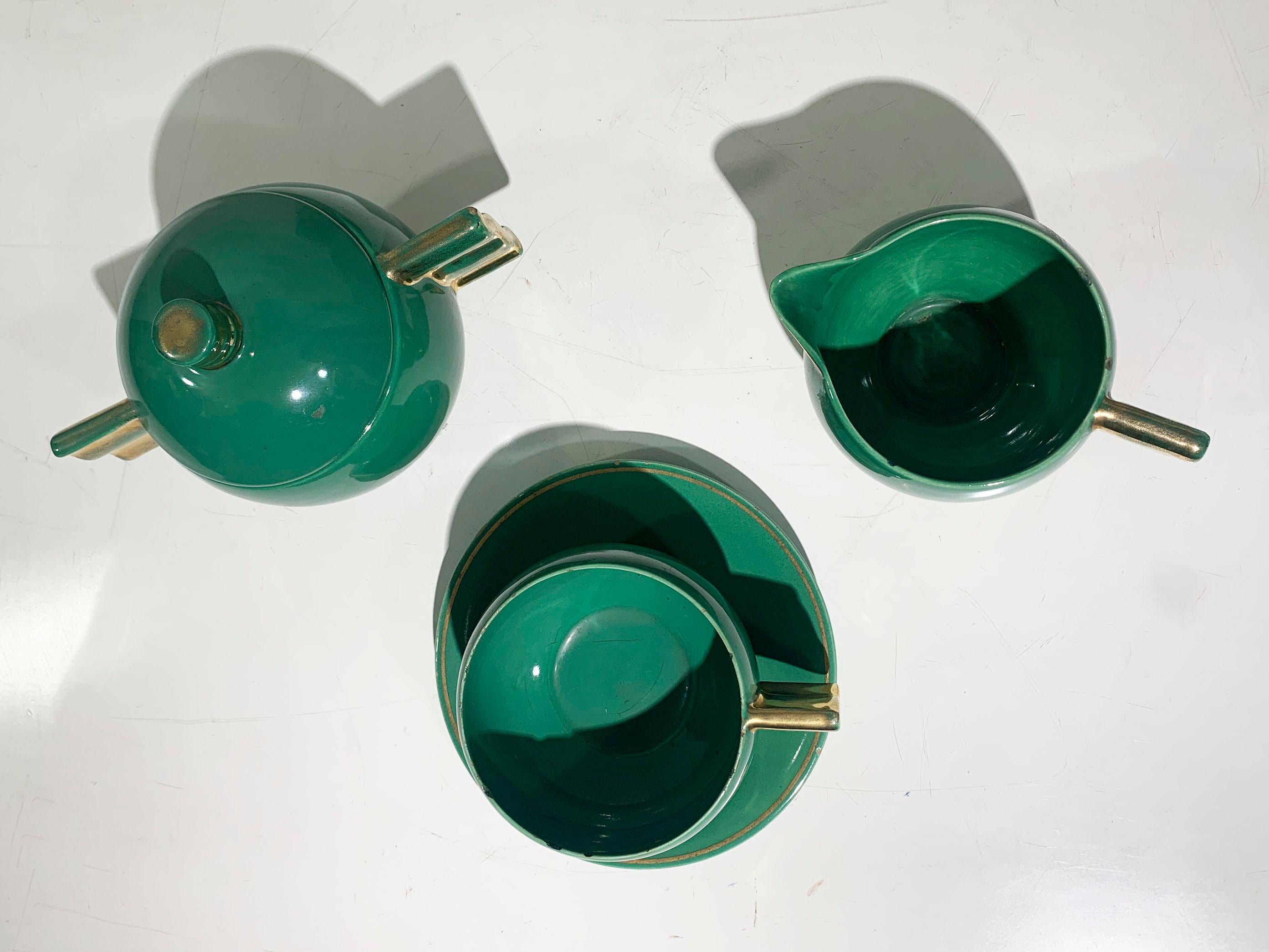 Este llamativo juego de té Art Déco de ROBJ Paris ejemplifica la audaz geometría y el lujoso acabado que definieron la época. 

Con un vibrante esmalte verde esmeralda combinado con ricos detalles dorados metálicos, este juego de tres piezas incluye
