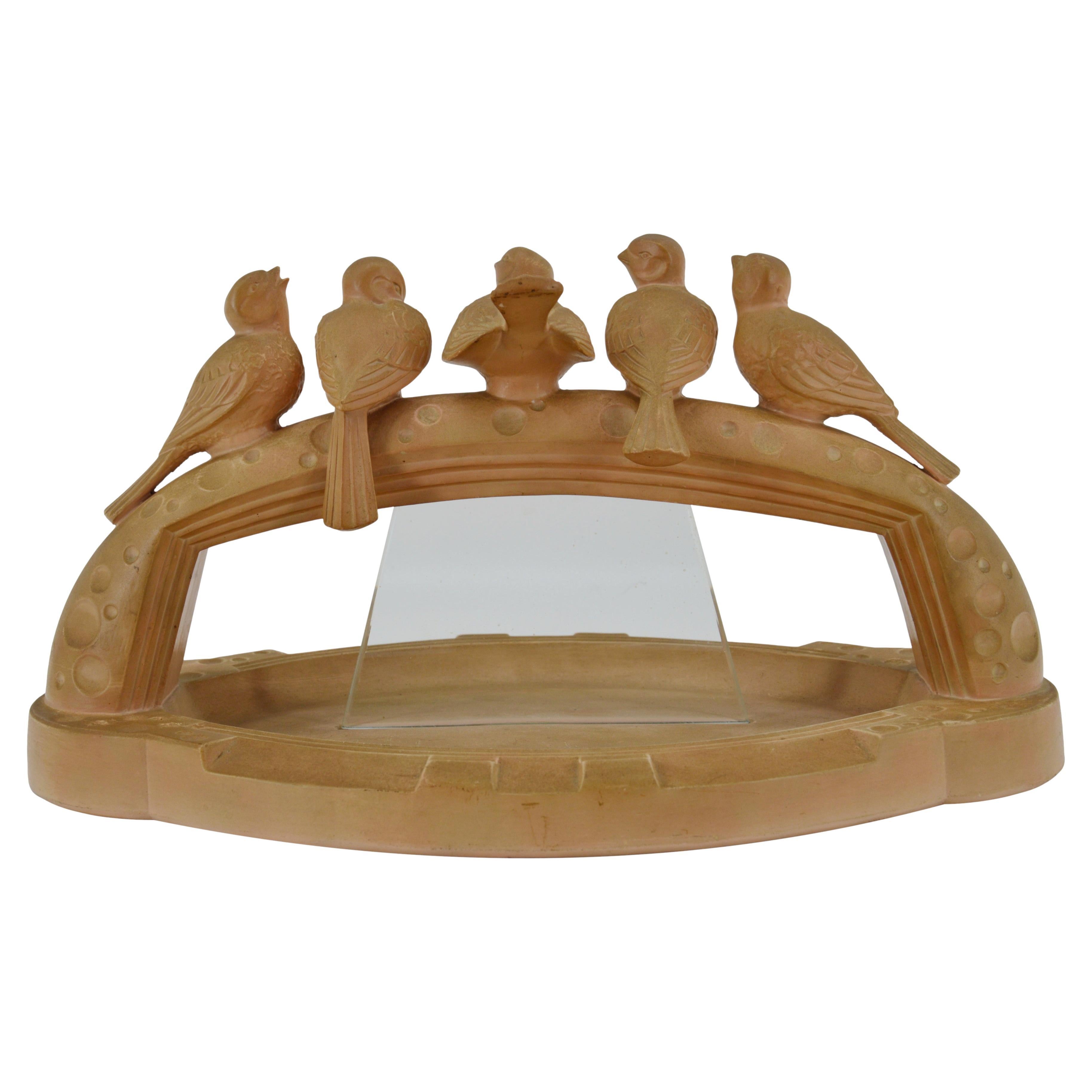 This French Art Deco terracotta sculpture, dating from the 1930s, features a stunning centerpiece with swallows. The piece combines terracotta and glass, showcasing the elegance and craftsmanship of the era. The swallows are beautifully rendered,