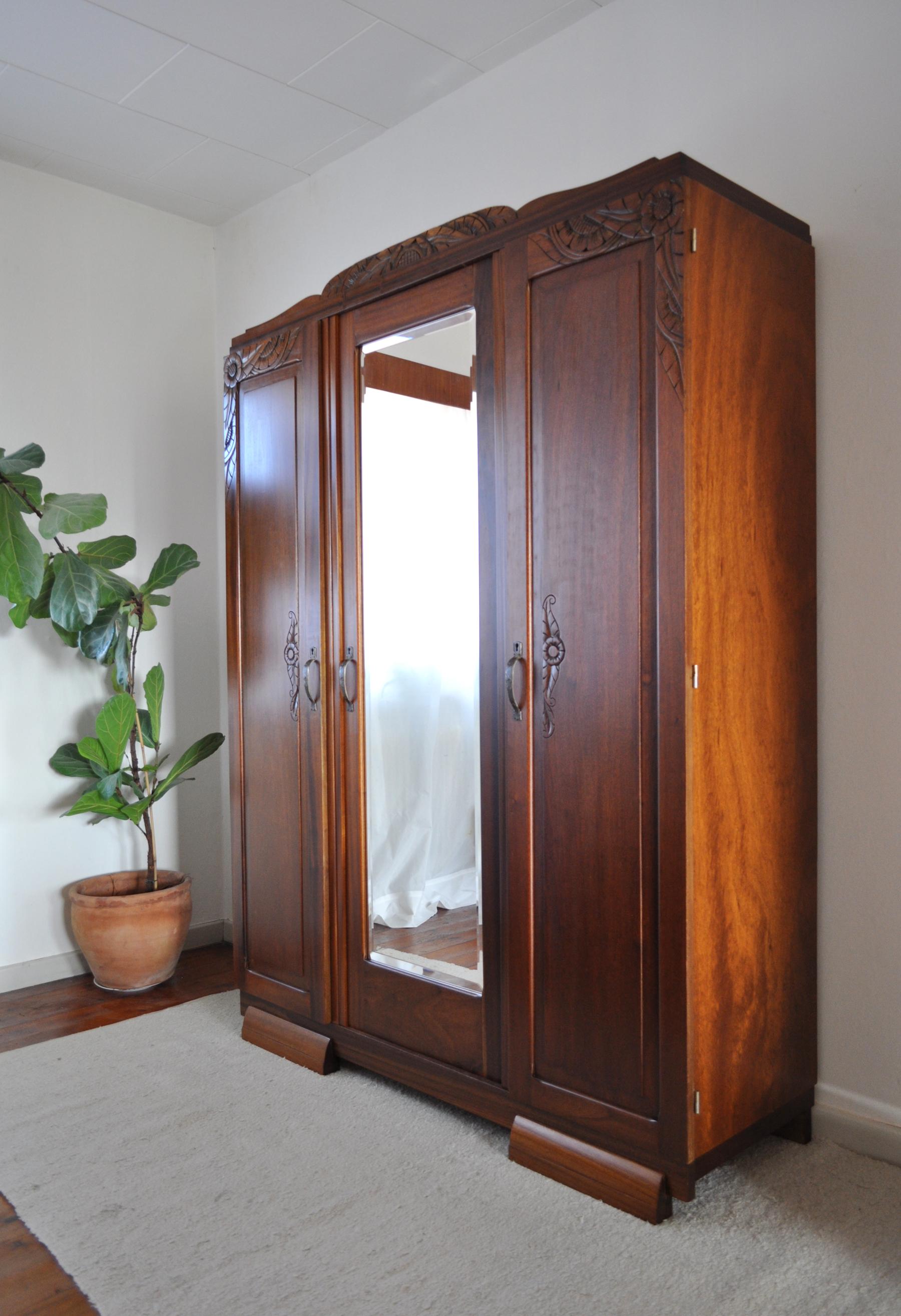 French Art Deco three-door cabinet in solid mahogany. Individually carved floral ornamentations, three shelves and a drawer. Faceted mirror and patinated brass handles.
Can be shipped disassembled.