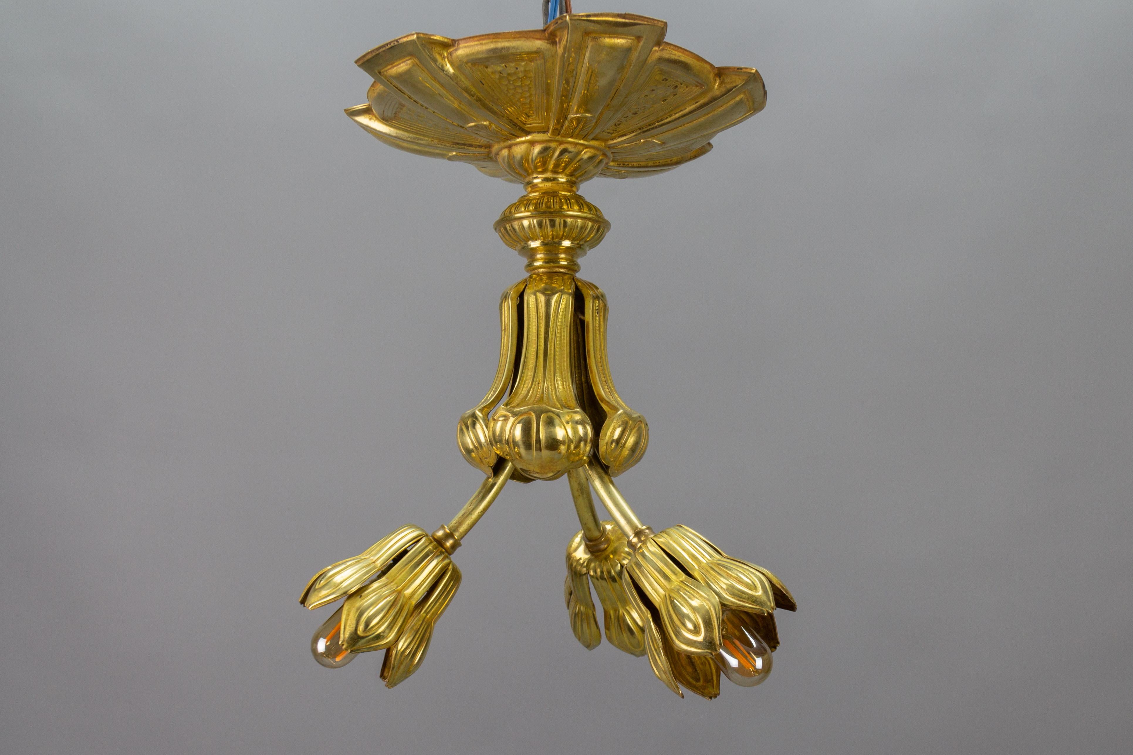 French Art Deco period three-light ceiling light fixture, from circa the 1920s.
This adorable and unusual Art Deco three-light ceiling lamp features an impressive and ornate ceiling canopy, and three brass arms each with a flower-shaped brass