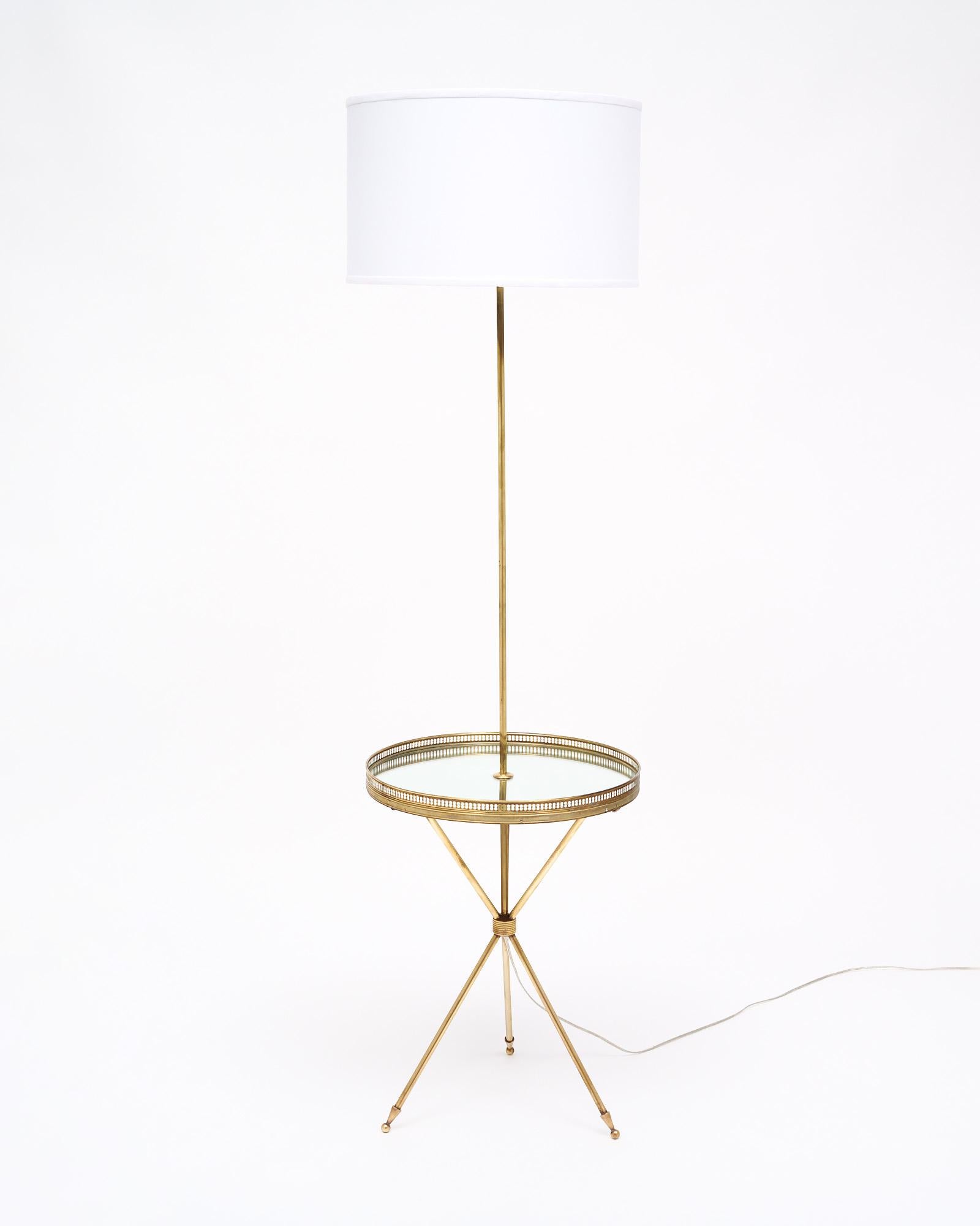 Art Deco period tripod floor lamp from France featuring a solid brass structure and a mirrored shelf surface. The shelf is encircled with a brass gallery. This piece has been newly wired to fit US standards. It is in very nice vintage condition with