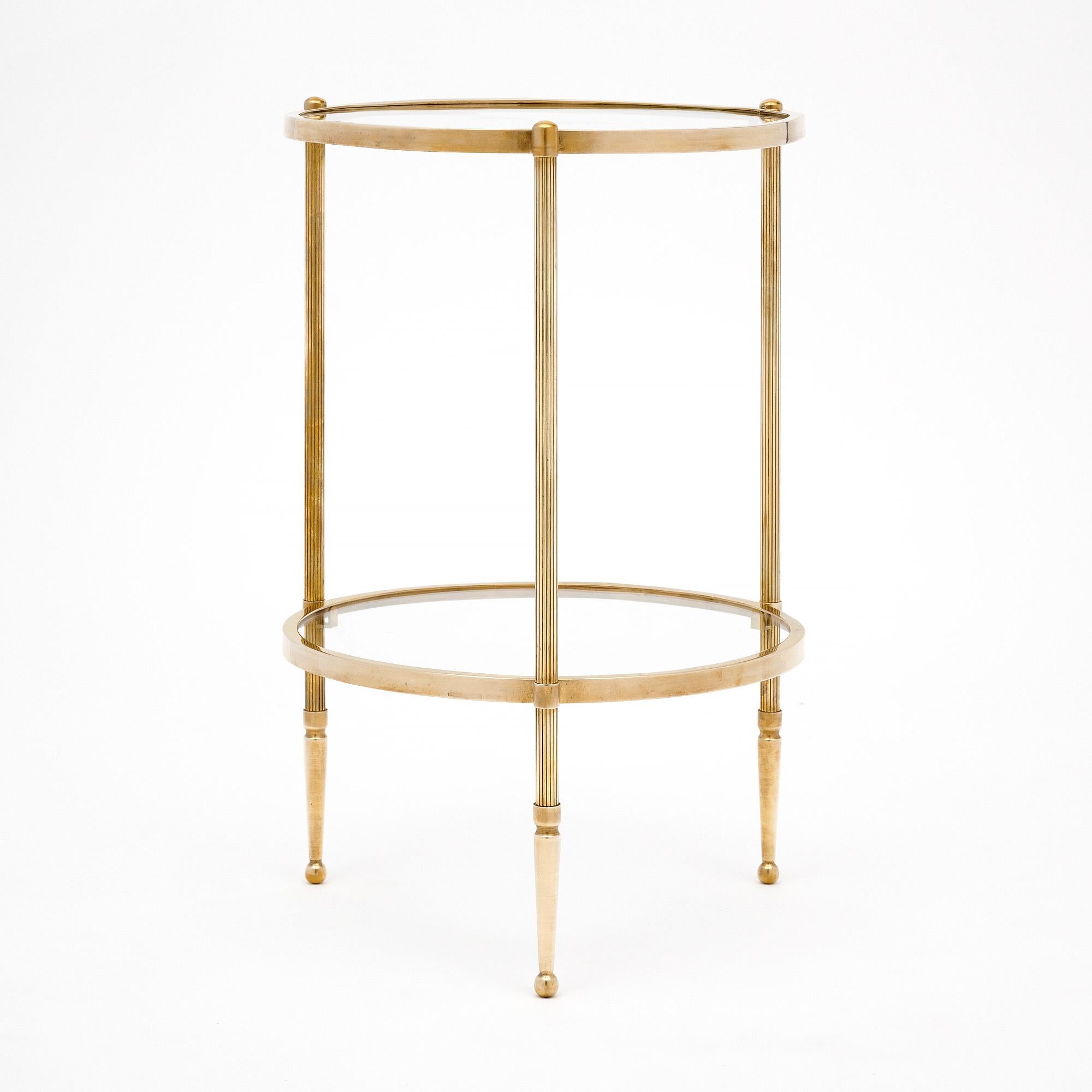 Side table from the Art Deco period in France. This table has tripod legs supporting two round glass shelves. The structure is made of a beautiful gilt brass. The table is in very nice vintage condition with only minor surface wear consistent with