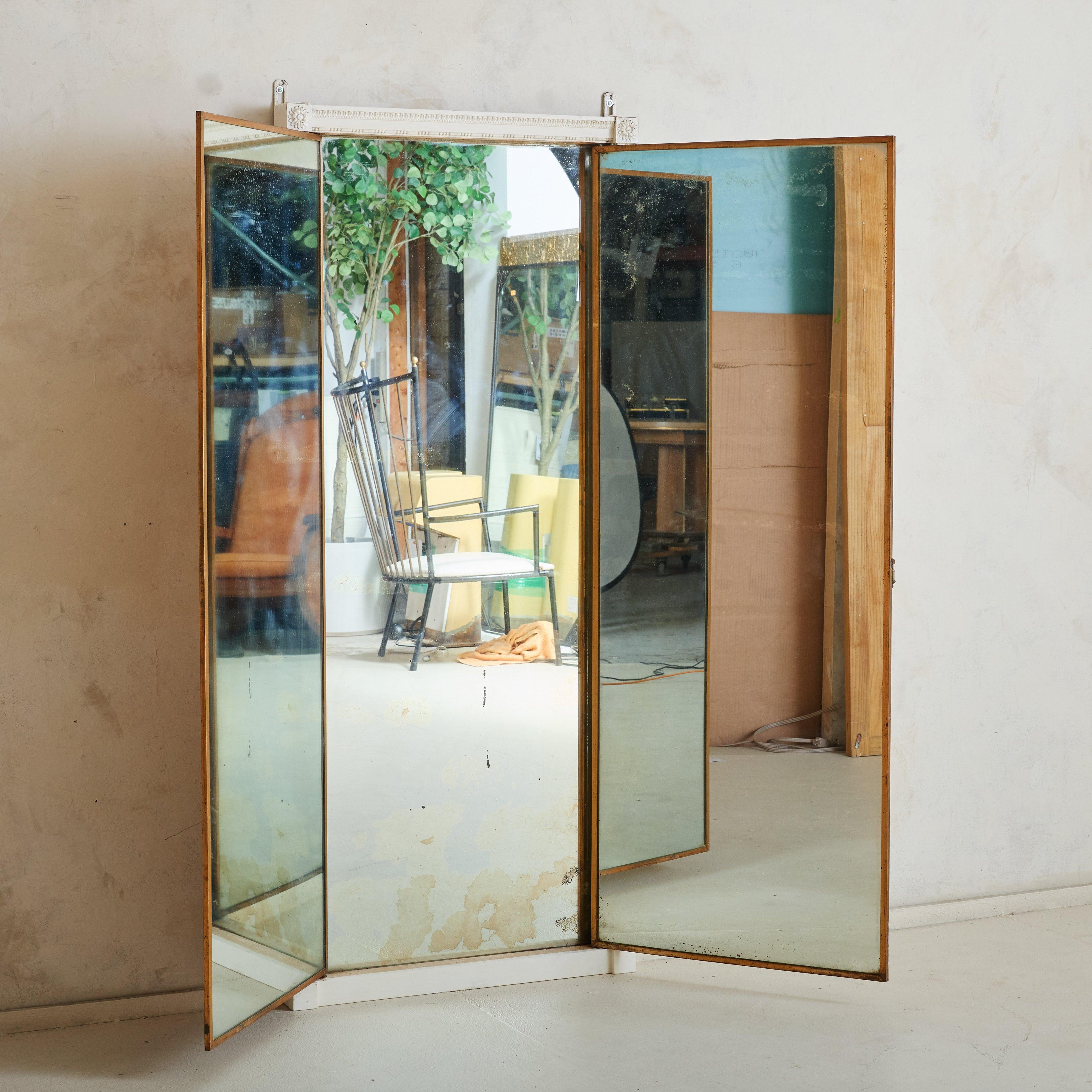 An understated piece by the iconic Brot Paris, this 1940s Art Deco triptych mirror is framed in ivory-painted wood with delicate hand-carved detailing. The mercury mirror glass features beautiful foxing, adding depth and character to the piece.