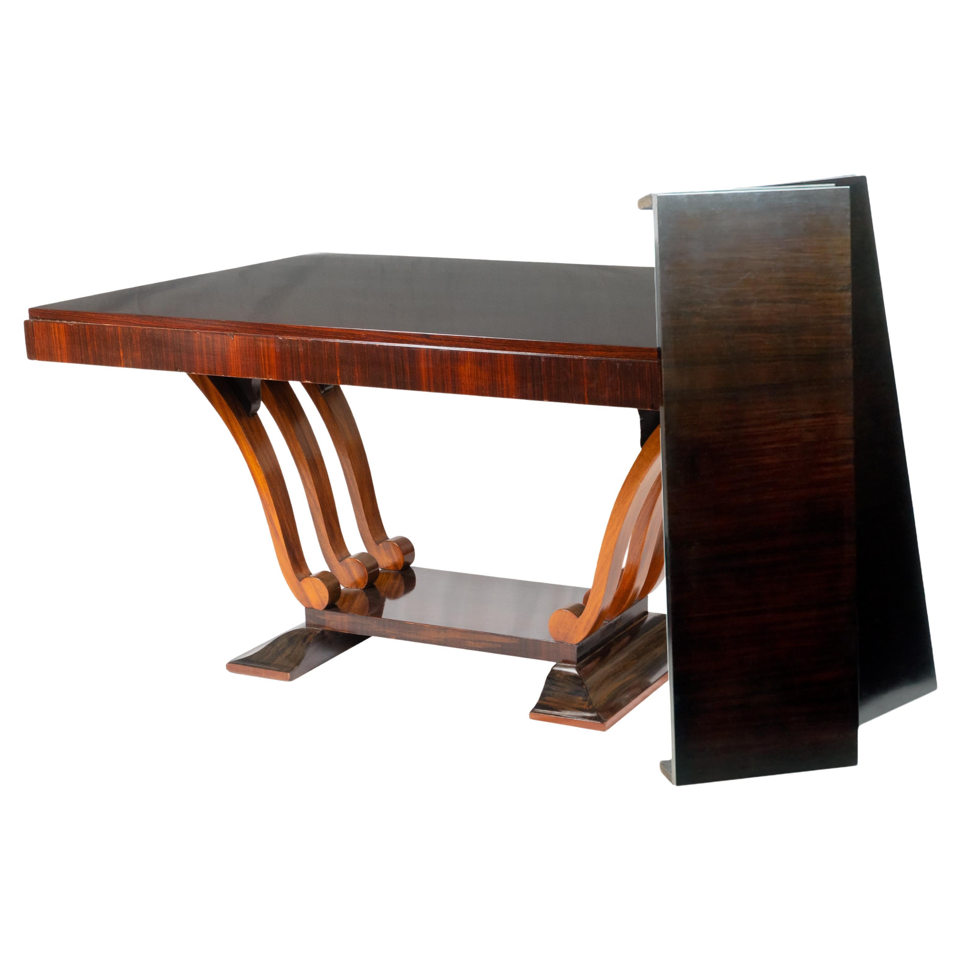 Esta impresionante mesa de comedor francesa (años 30) presenta una clásica mesa de comedor de parquet barnizado con patas redondeadas y una estructura en forma de arpa, con extensiones, todo un ejemplo de geometría y curvatura en el periodo Art