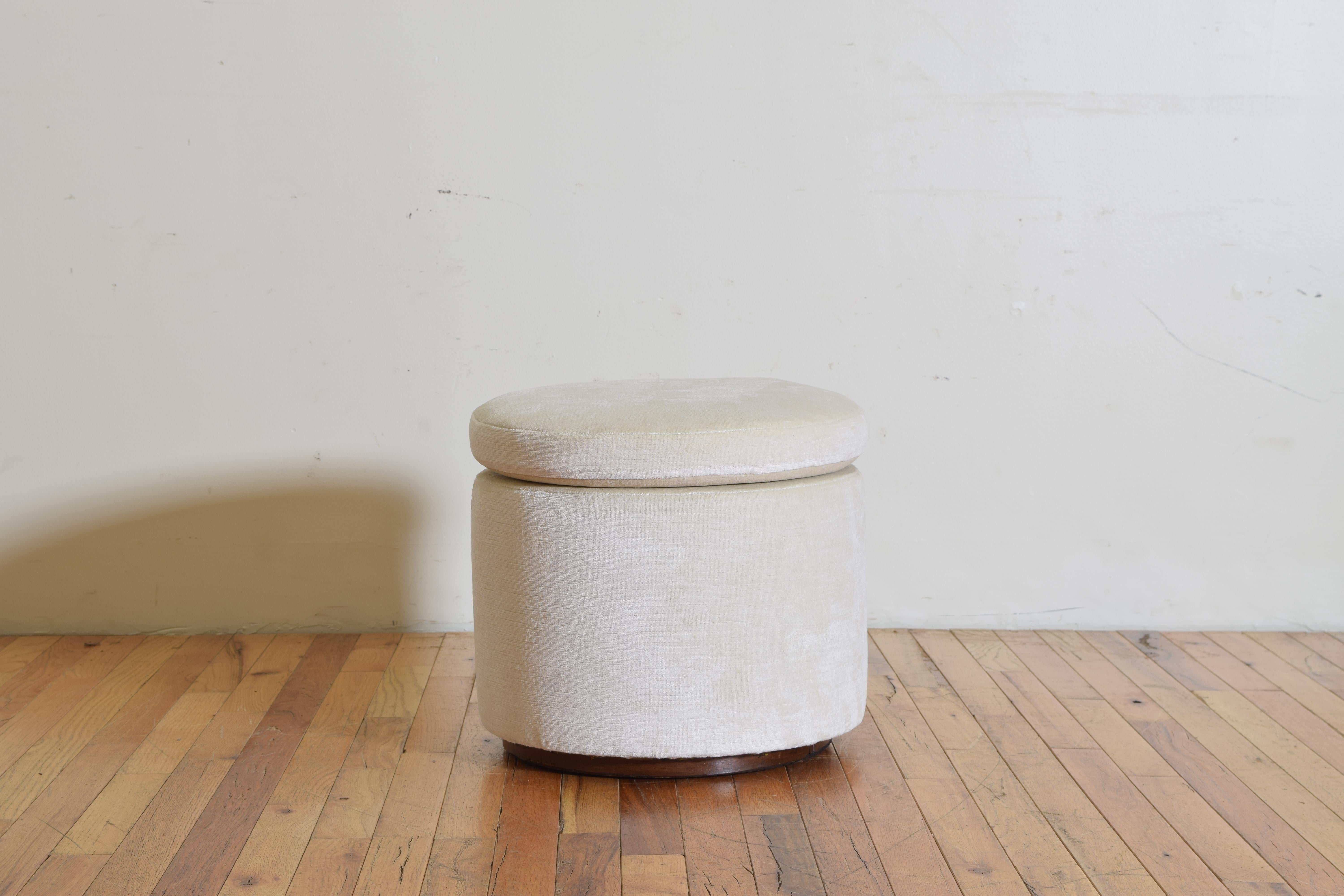Of cylindrical form with an upholstered body, loose cushion, and a band of walnut veneer on a slightly recessed base, second quarter of the 20th century.