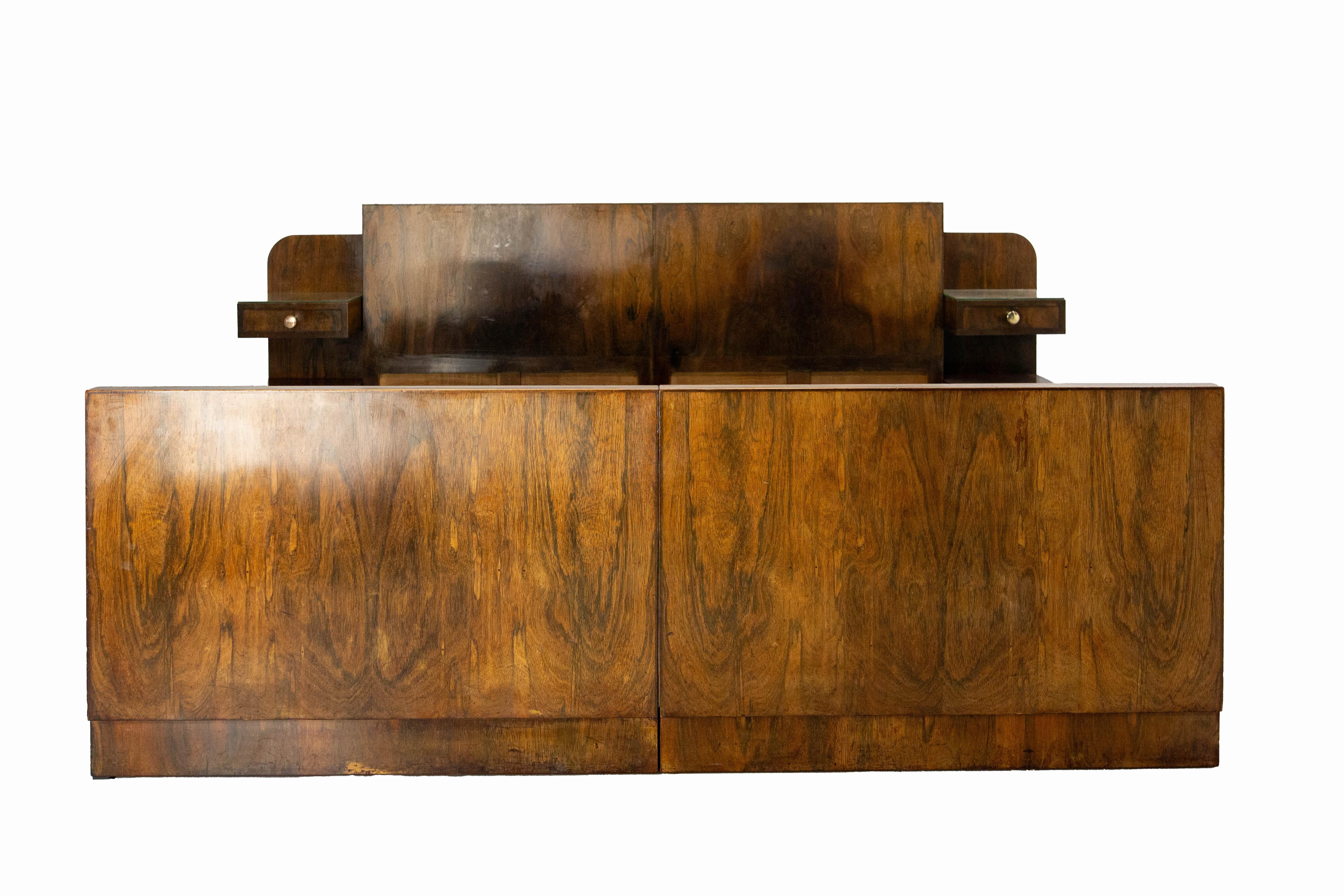 French bed made circa 1930, in the art deco period and style. 
The bedside cabinets are integrated into the headboard: each is covered with a mirror and contains a drawer and a small cupboard. The knobs are in bronze.
As you can see on the last