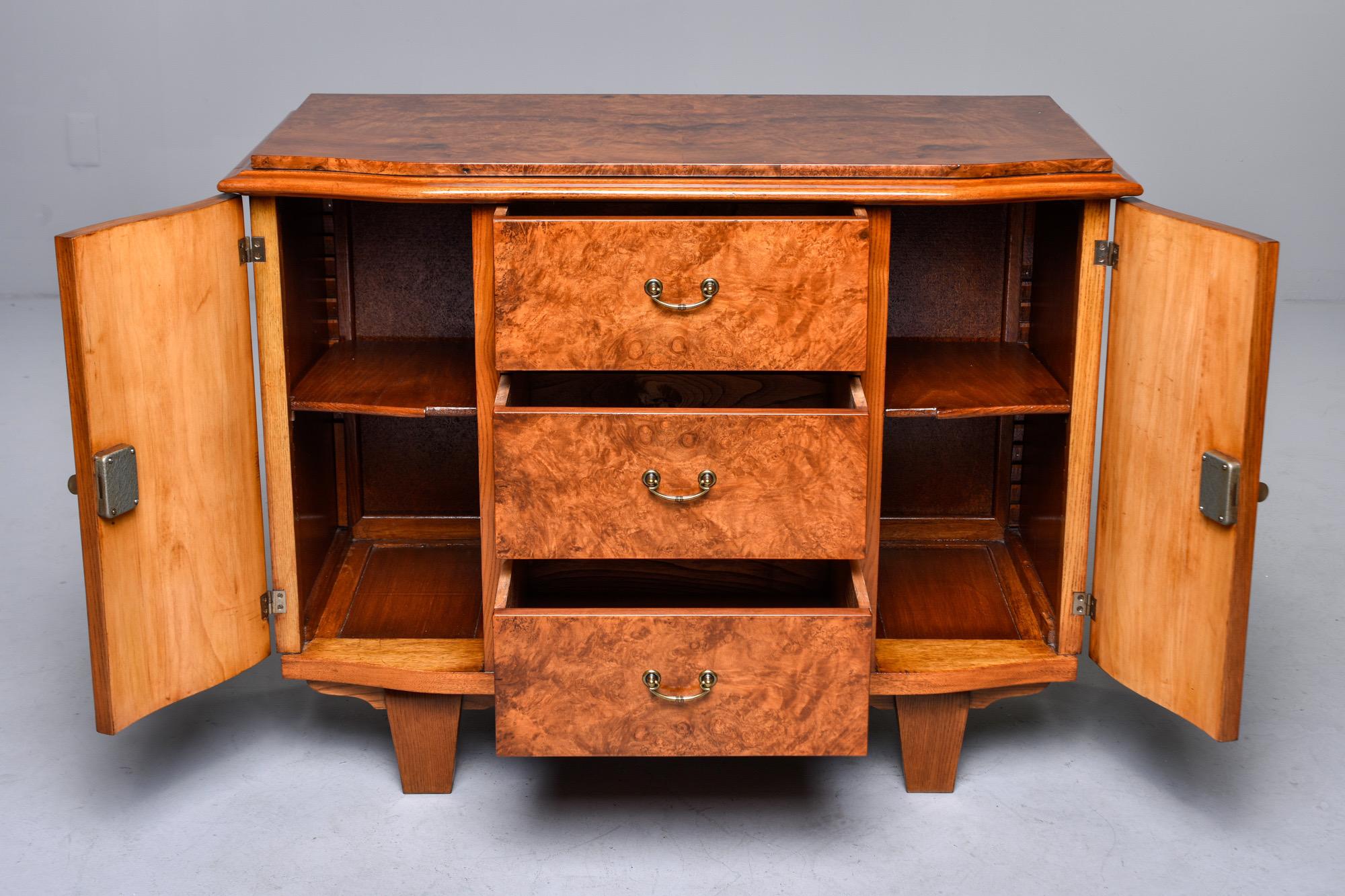 French Deco style commode in walnut veneer features original brass hardware, three center drawers flanked by side cabinets with one internal shelf on each side, circa 1930s. Unknown maker.