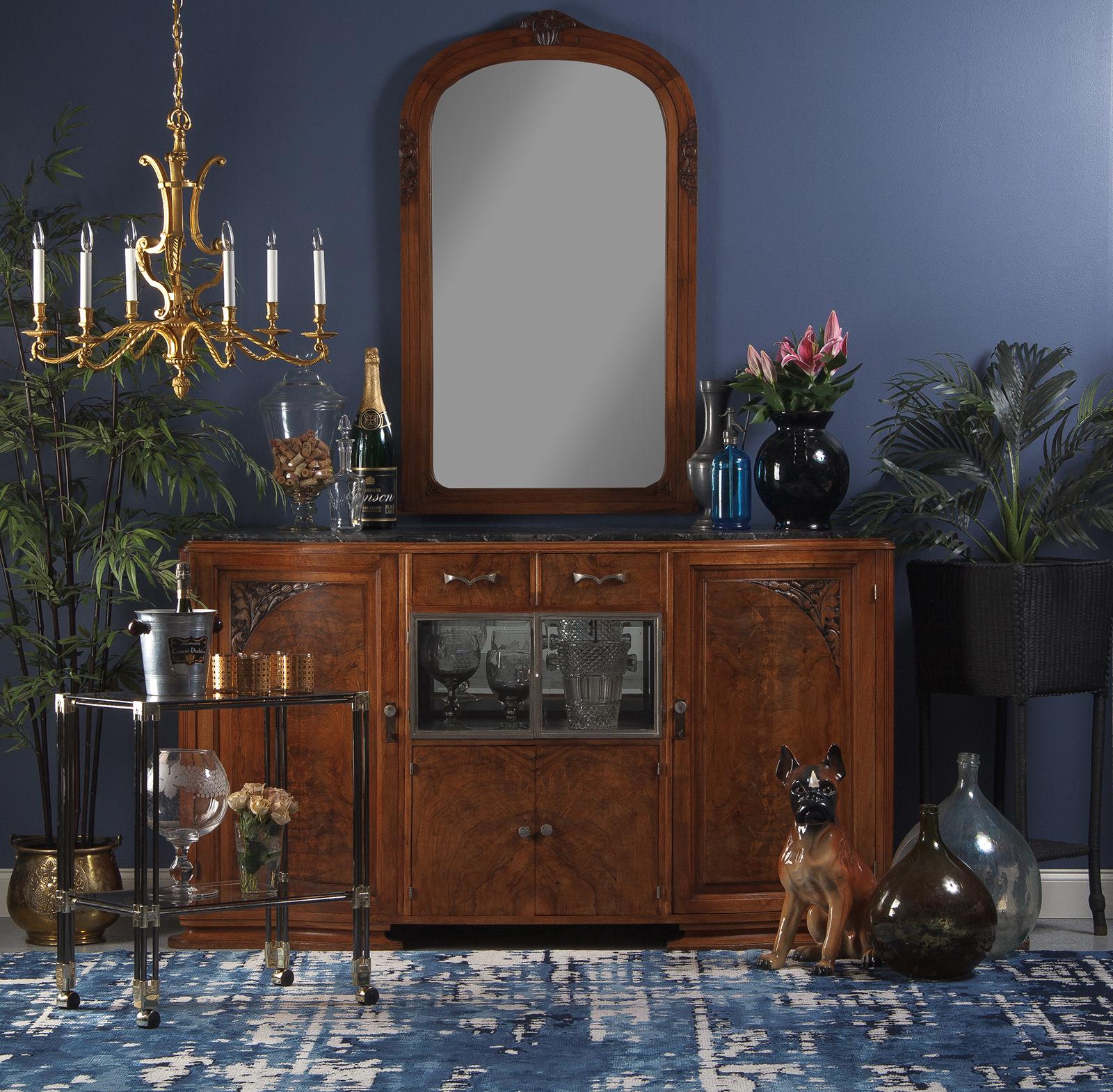 A French Art Deco period Mirror, circa 1930s with a walnut frame and a beveled mirrored glass. The triple edge frame has an arched top, some floral designs and scrolls. The mirror is rounded at edges.
