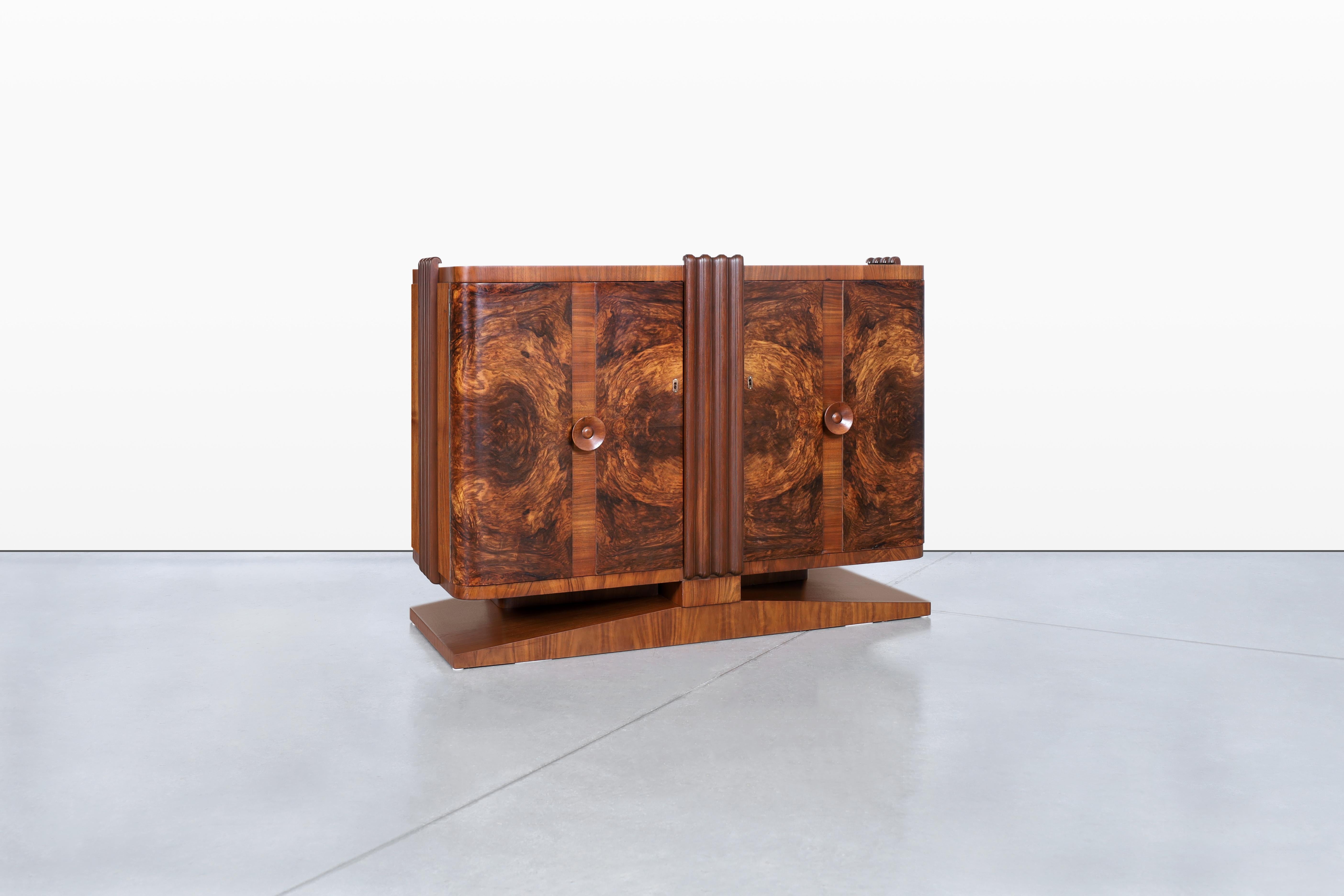 Fai un salto indietro nel tempo con questa splendida credenza art déco vintage, un capolavoro francese degli anni '30 che combina senza sforzo eleganza e funzionalità. Il mobile è dotato di due grandi ante, che mostrano una venatura esotica del