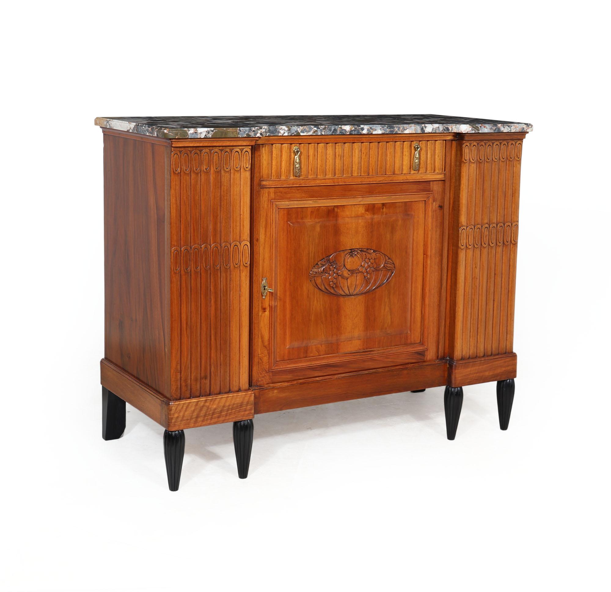 A great quality French Art Deco sideboard in solid oak and solid walnut, having a marble top with single drawer and cupboard below, reeded detail sides and drawer with gilded bronze hardware, the central cupboard has crisply carved fruit bowl