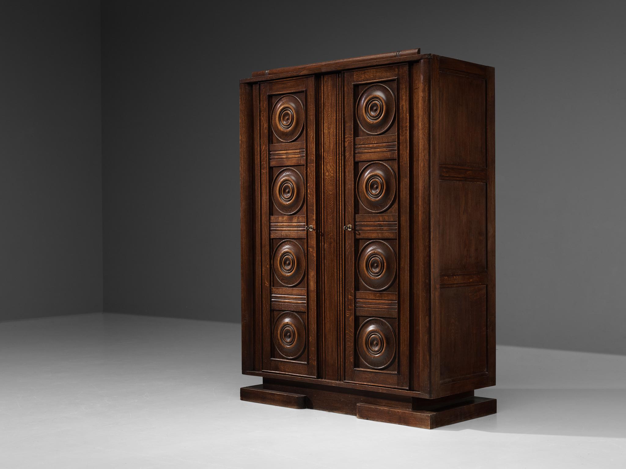 Wardrobe, oak, France, 1930s 

This sturdy wardrobe shows the typical characteristics of French Art Deco. The dynamic carved door panels show some interesting graphically patterns. Mark the beautifully shaped rounded forms adding some elegancy to