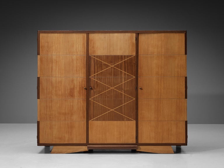 Large cabinet or wardrobe, oak, walnut, veneer, brass, France, 1930s

Large Art Deco French wardrobe unit with three doors. The middle doors has a geometric pattern in lighter wood that catches the eye straight away. Also, note the beautiful base of