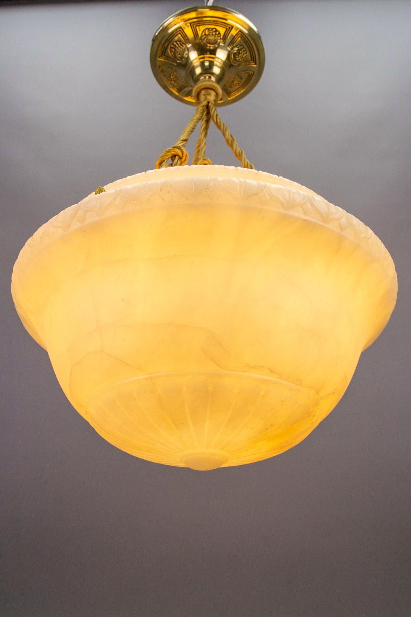 An awesome Art Deco white color alabaster pendant ceiling light fixture. France, circa the 1920s. 
This beautifully shaped and gracefully carved alabaster bowl with leaf carvings and a round finial is suspended by three ropes (wires) and an elegant,
