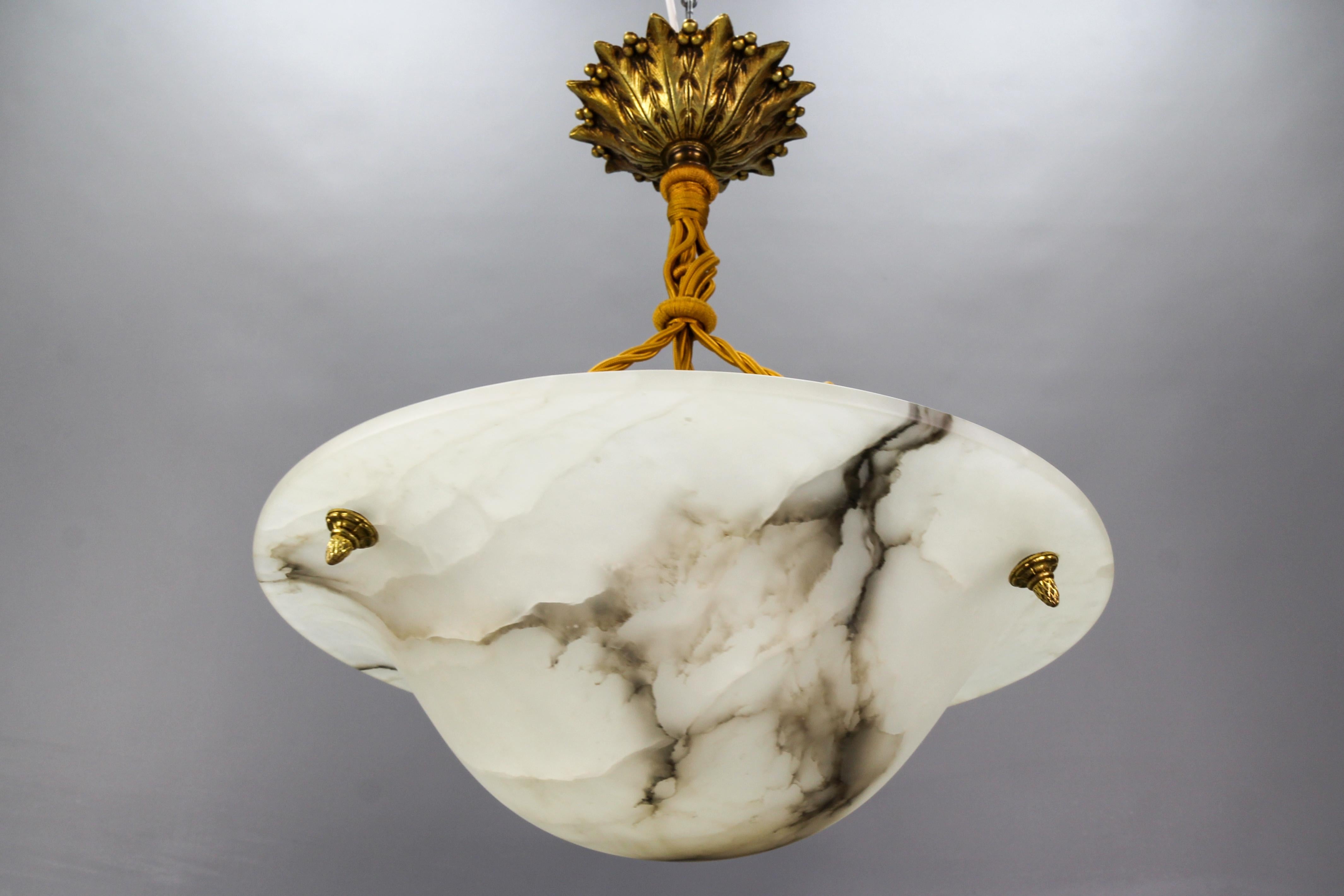 Art Deco white and black veined alabaster pendant light fixture.
A wonderful alabaster pendant ceiling light fixture from circa the 1920s. Beautifully veined and masterfully carved one-piece white alabaster bowl suspended by three ropes (wires) and