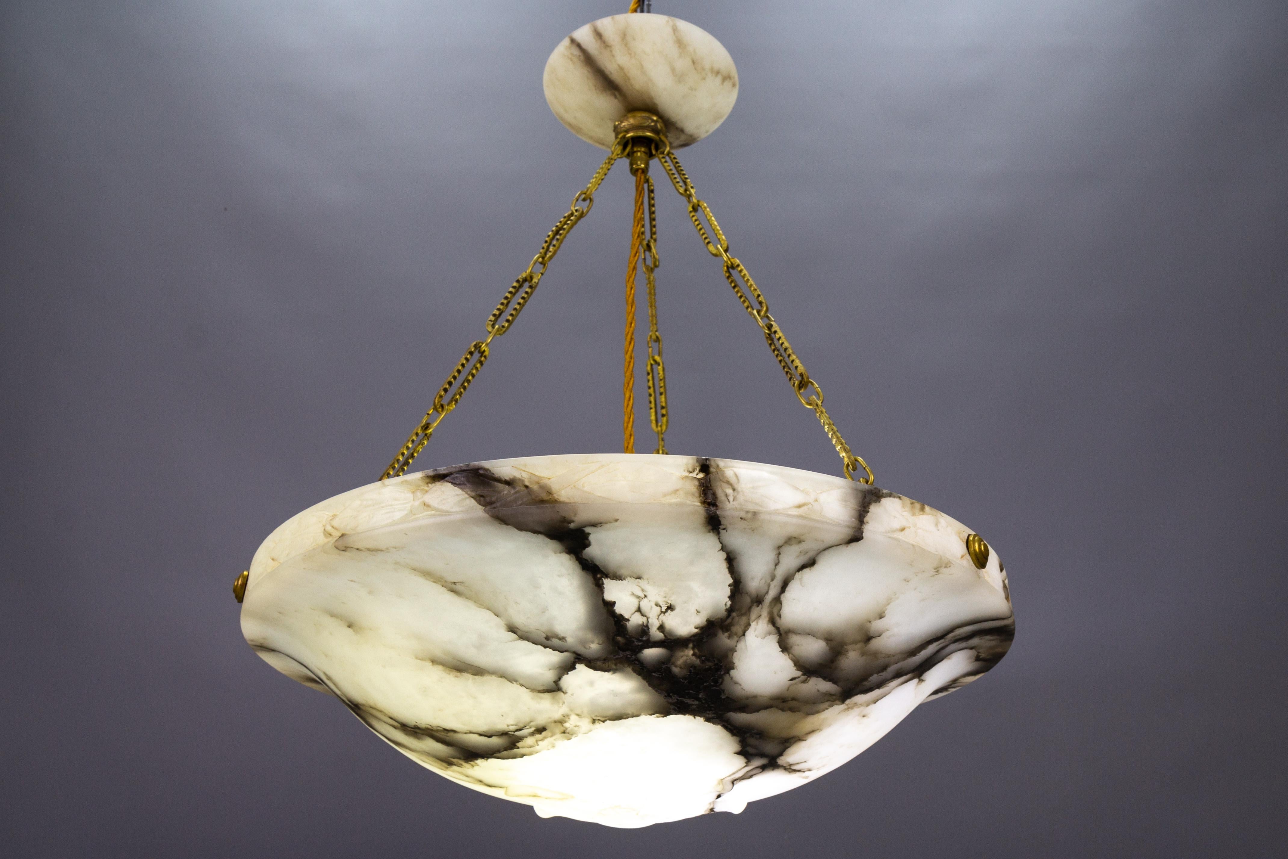 Antique French Art Deco black veined white alabaster pendant light fixture.
Gorgeous alabaster pendant ceiling light fixture from circa 1920. Beautifully veined and masterfully carved soft white alabaster bowl suspended by three brass chains and an