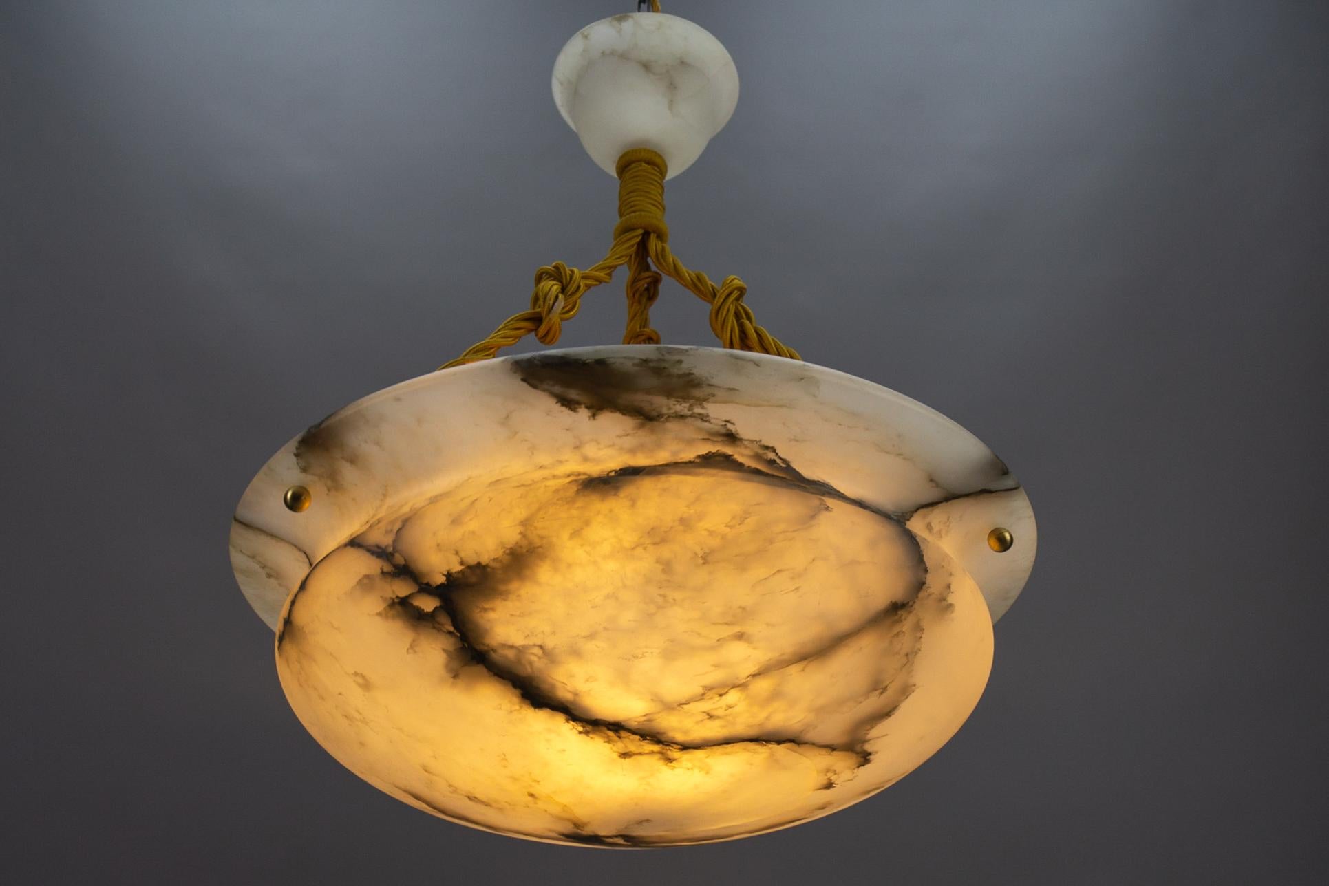 Antique French Art Deco black veined white alabaster pendant light fixture.
Gorgeous and beautifully shaped alabaster pendant ceiling light fixture from circa 1920. Superbly veined and masterfully carved white alabaster bowl suspended by three ropes
