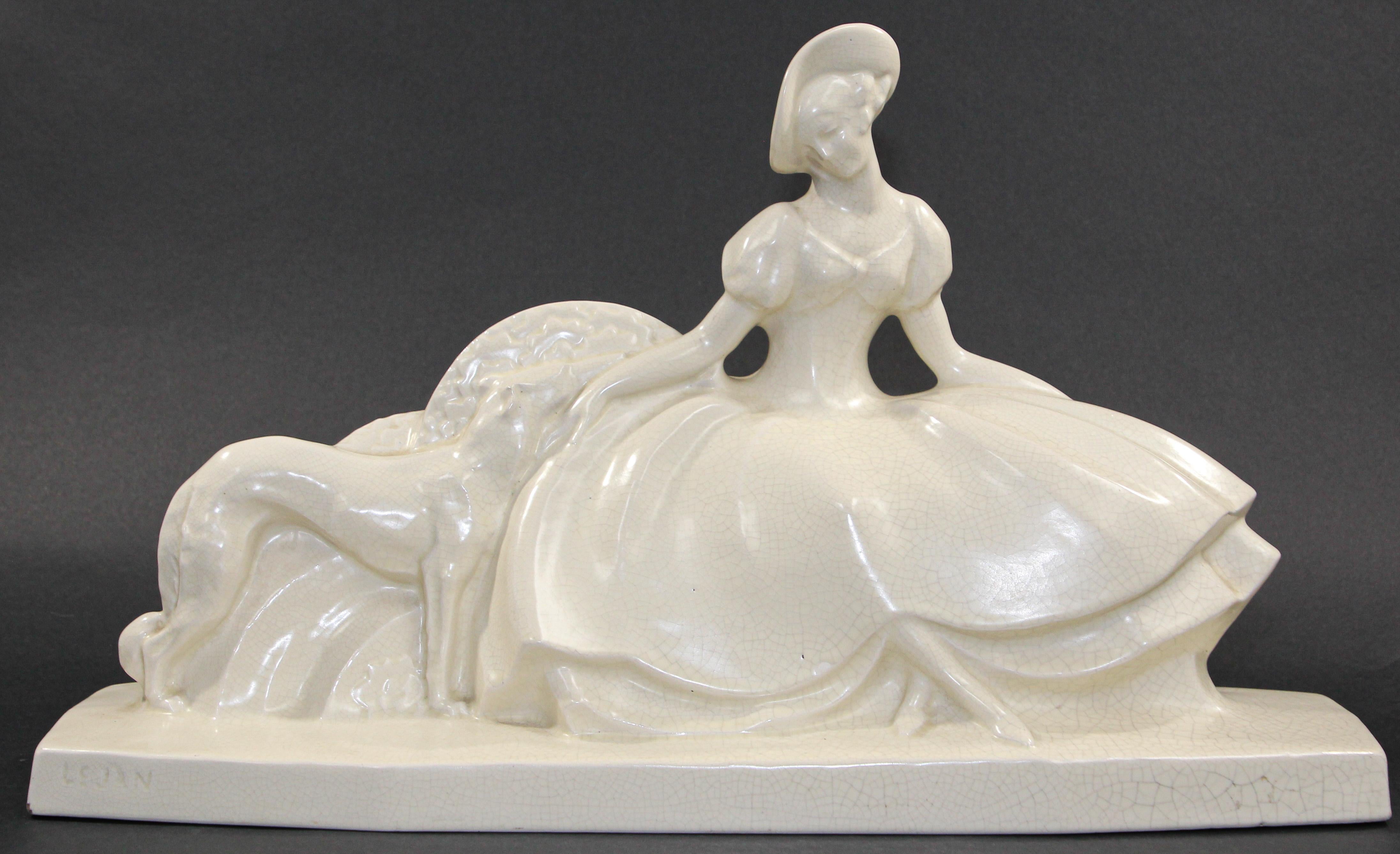 Art Deco Lejan French pottery craquelé glazed.
An Art Deco Lejan French pottery craquelé glazed figure group, lady wearing a crinoline dress accompanied by a greyhound, raised on a shaped octagonal base, impressed factory mark to edge of