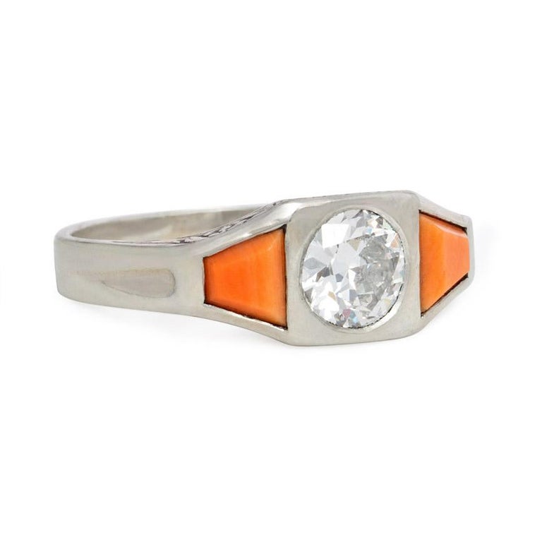 An Art Deco diamond and coral ring, the center diamond flanked by coral trapezoids in 18k white gold with engraved gallery. France.  Atw diamond 0.75 ct.

Dimensions: width across finger approximately 5/8