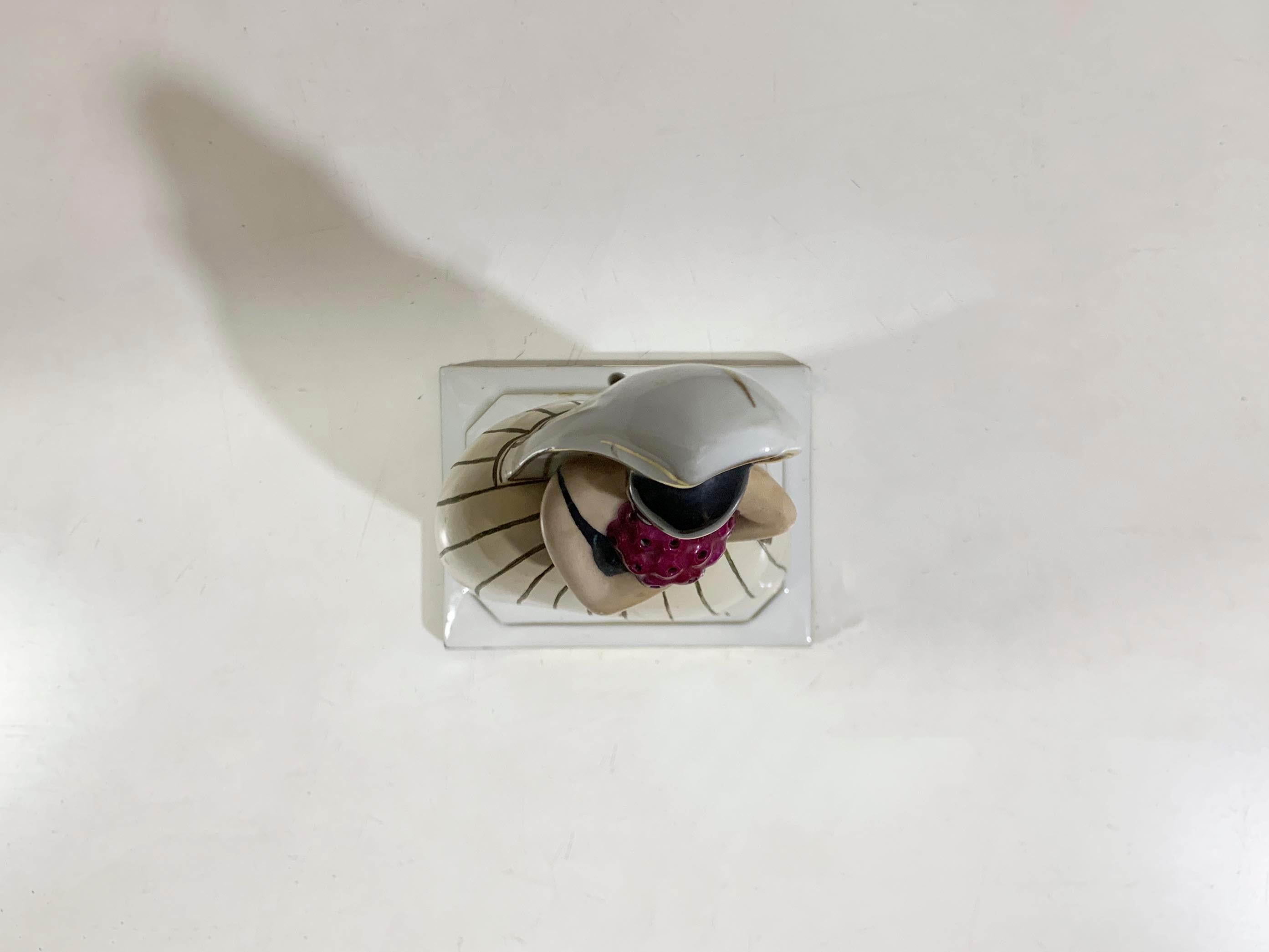 Este difusor de perfume de Robj Paris es una elegante pieza de porcelana Art Decó, con una figura femenina estilizada que sostiene un ramo de flores violetas en los brazos y que sirve también de difusor/portaperfumes o aceites esenciales y de