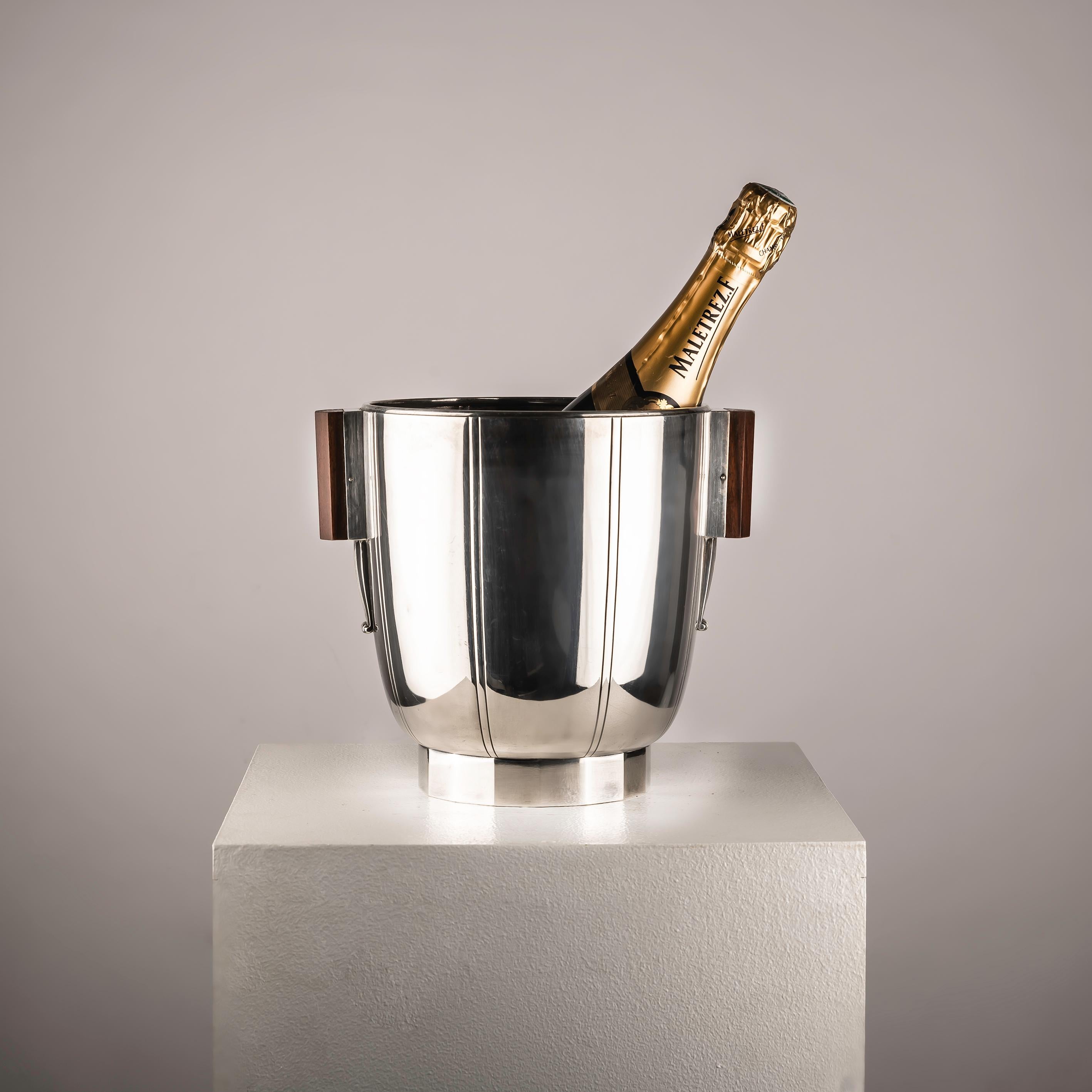 This French Art Deco Wine Cooler from the 1930s is a truly exceptional piece that exudes elegance and sophistication, making it both unique and special. Crafted from silvered metal with exquisite wood handles, it embodies the epitome of Art Deco