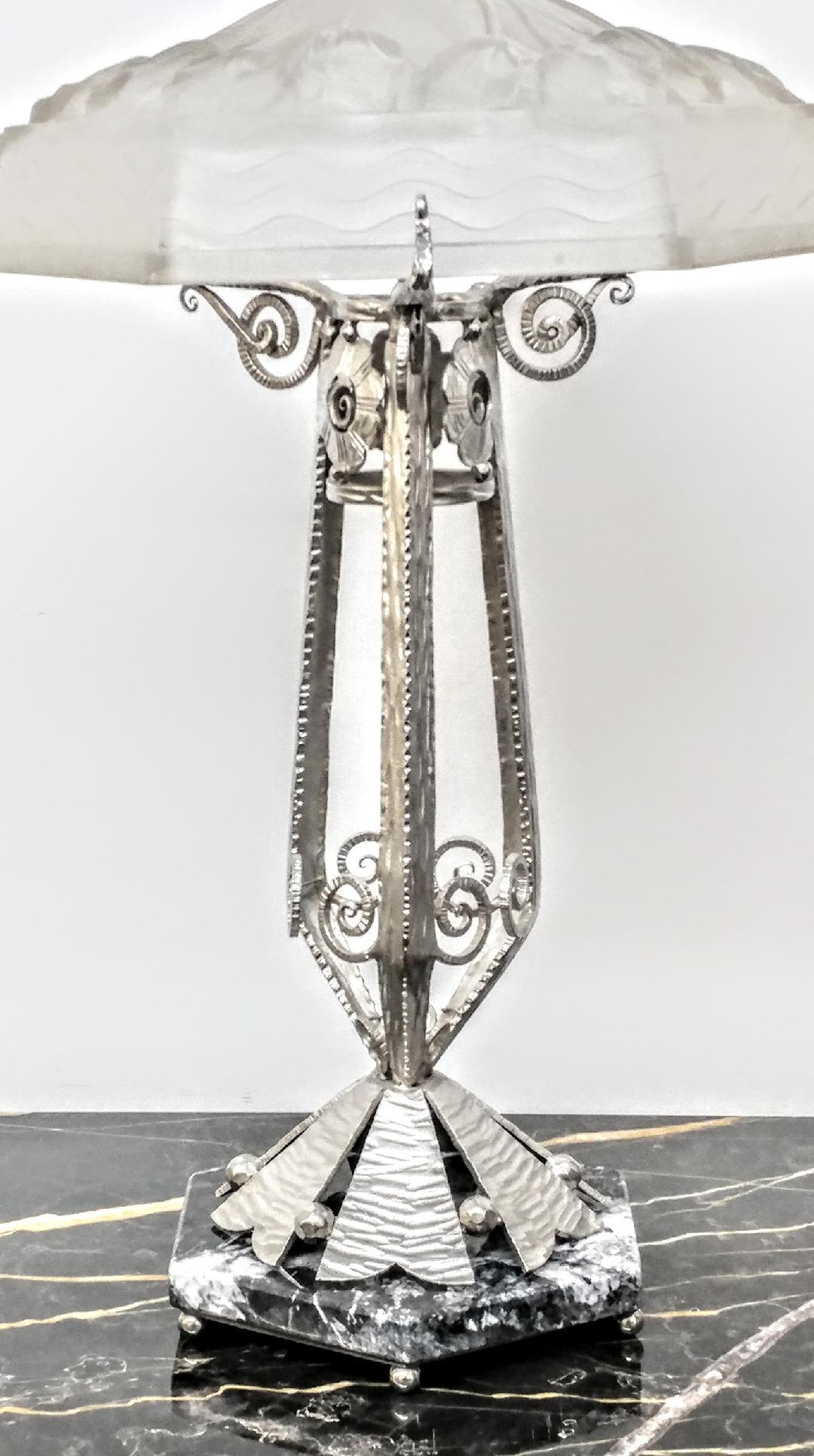 French Art Deco hand forged wrought iron table lamp in great condition. Decorated with fine intricate stylized symmetric with geometric scrolled and flower motif and detailed throughout with a tulip motif glass shade. The fixture was replated in