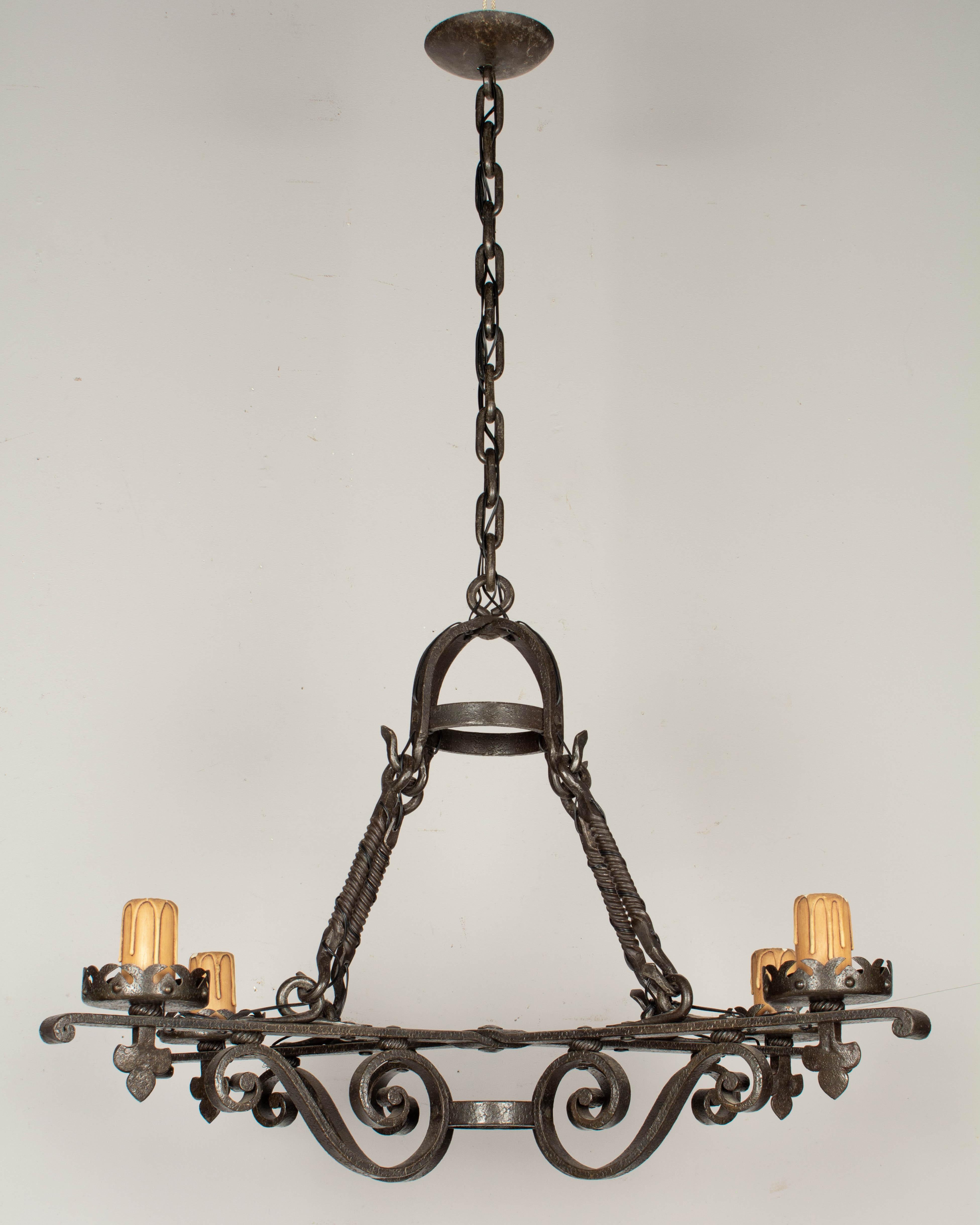 A heavy French Art Deco four-light wrought iron scroll form rectangular chandelier. Exceptional craftsmanship. In working condition, rewired with new sockets. Original candle covers, thick chain and canopy. 
Measures: 26