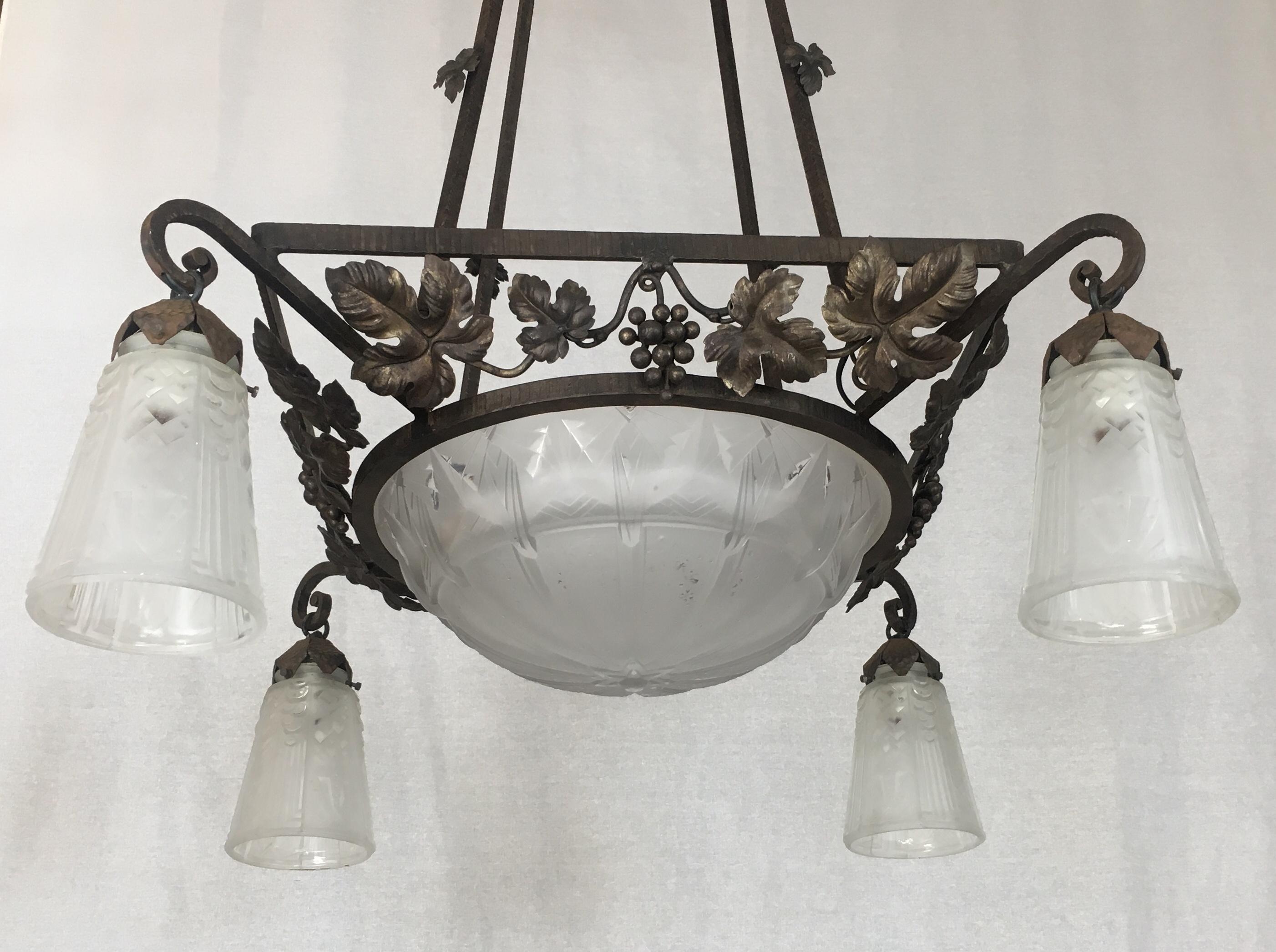Un superbe luminaire Art déco classique de Muller Frères. Ce lustre accrocheur en fer forgé est doté d'un dôme en verre dépoli et gravé et d'abat-jours en trompette aux formes géométriques. Fabriqué à la main au début du 20e siècle, vers 1930. Ce