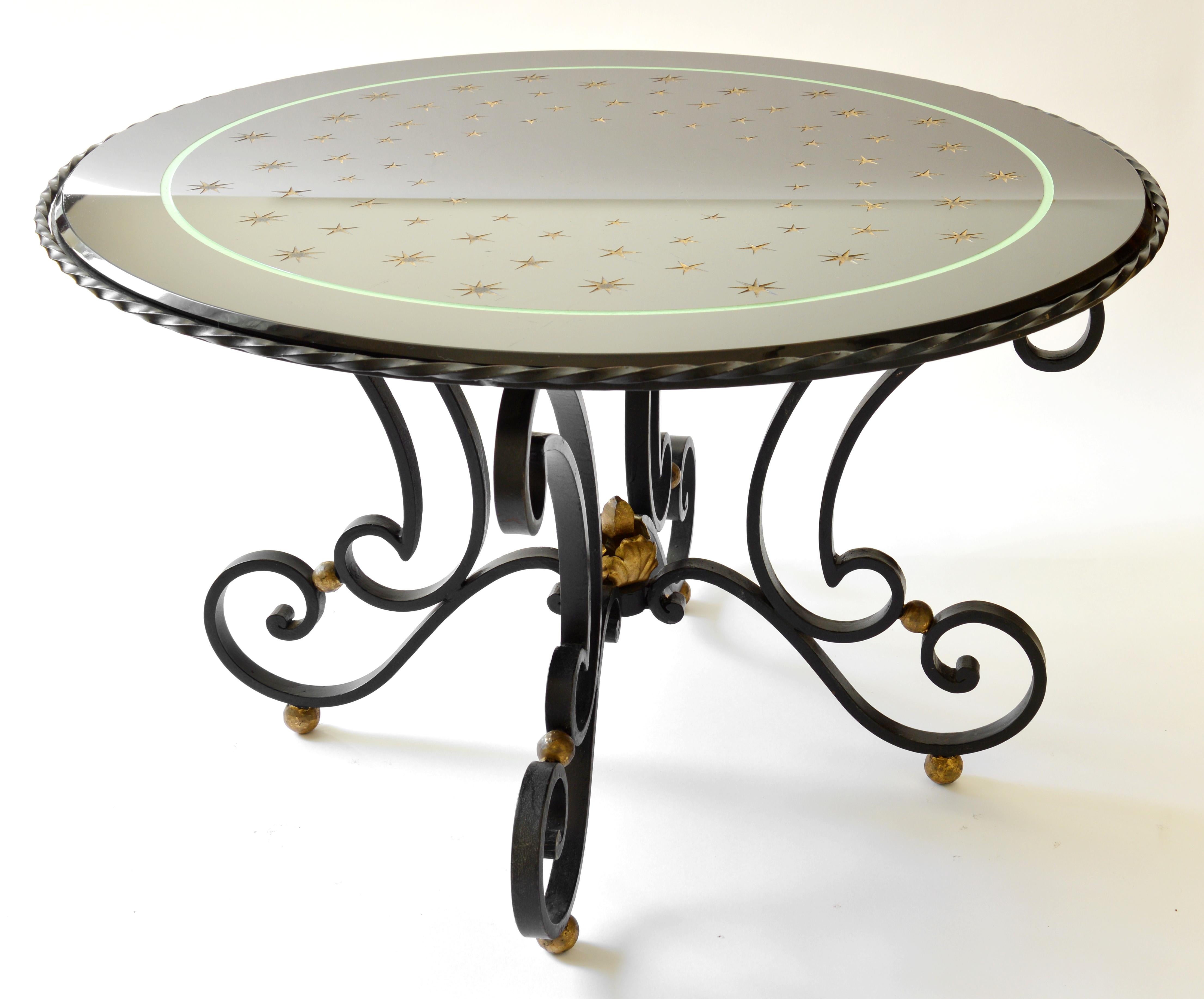 French Art Deco coffee table, France, late 1930s. Wrought-iron base with some gilded parts. The top, made of black glass, shows a swarm of stars shining in the night as the Milky Way. These stars are acid-etched and gilded. Height : 48cm - 18.9in,