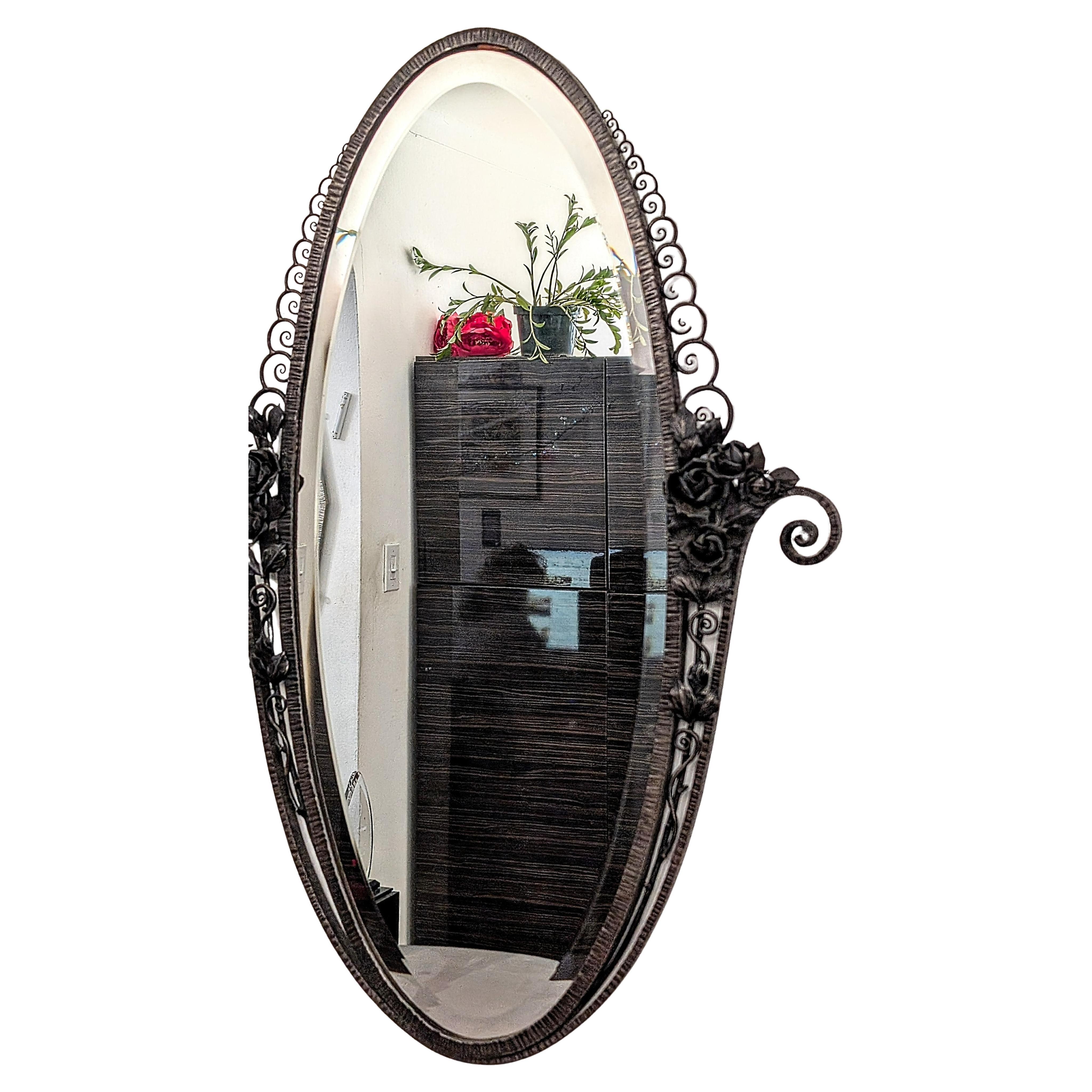 Uno splendido e raro specchio francese Art Deco di forma ovale in ferro battuto, circondato da intricati fiori e foglie con volute in una texture martellata. Siamo la rara fonte specializzata in Art Deco francese da oltre tre decenni, dal 1991, con