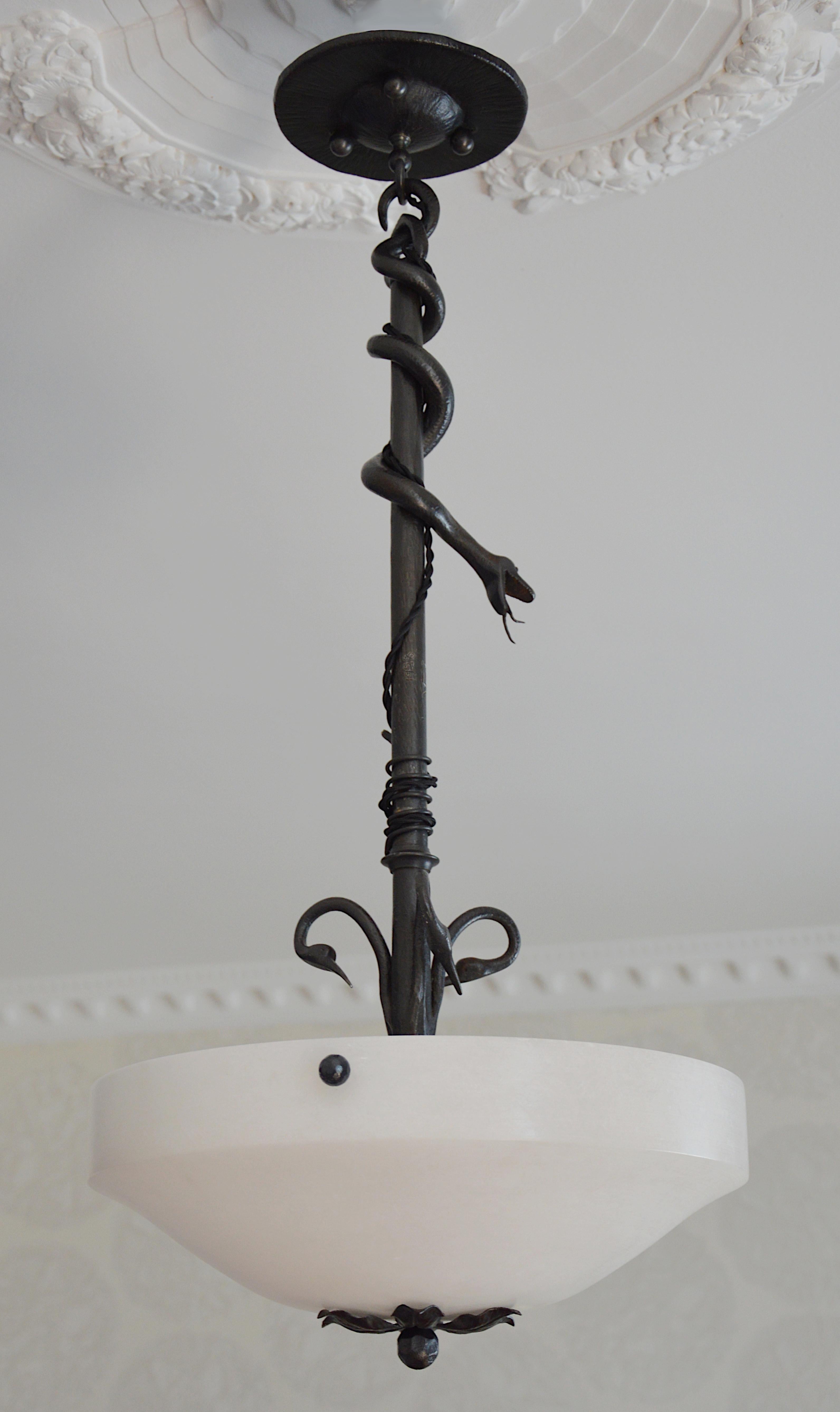 Lustre à suspension Art déco, France, 1928. L'abat-jour en albâtre est accroché à son cadre en fer forgé. Un serpent descend vers 3 oiseaux aux longs becs. Cette pièce inédite est un bijou. Mesures : Hauteur 28.8