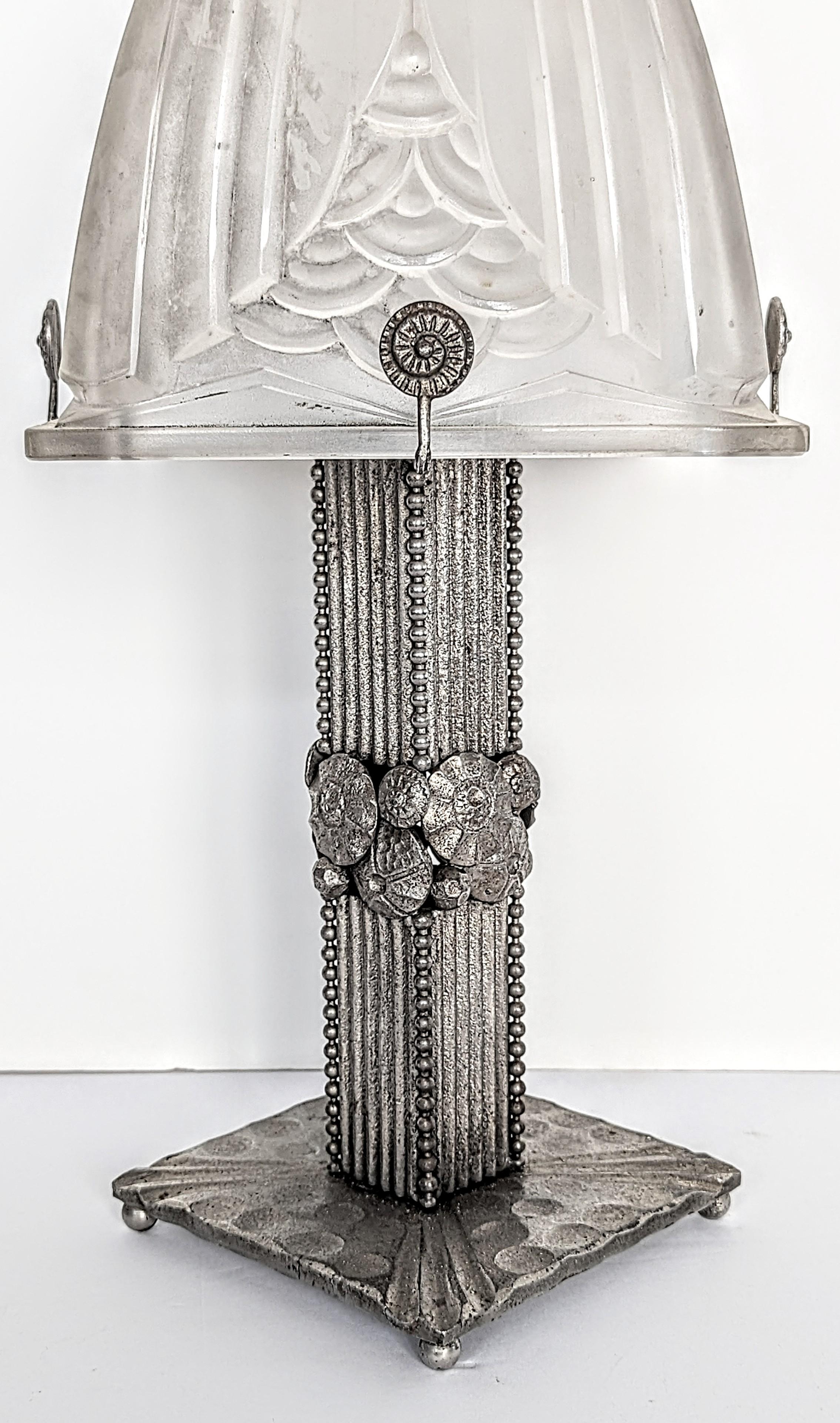 A rare French Art Deco hand-forged wrought iron table lamp embracing a glass shade Signed by the French artist Schneider in great condition. Decorated in stylized geometric floral motifs. Rewired to U.S. standards which accommodate one household