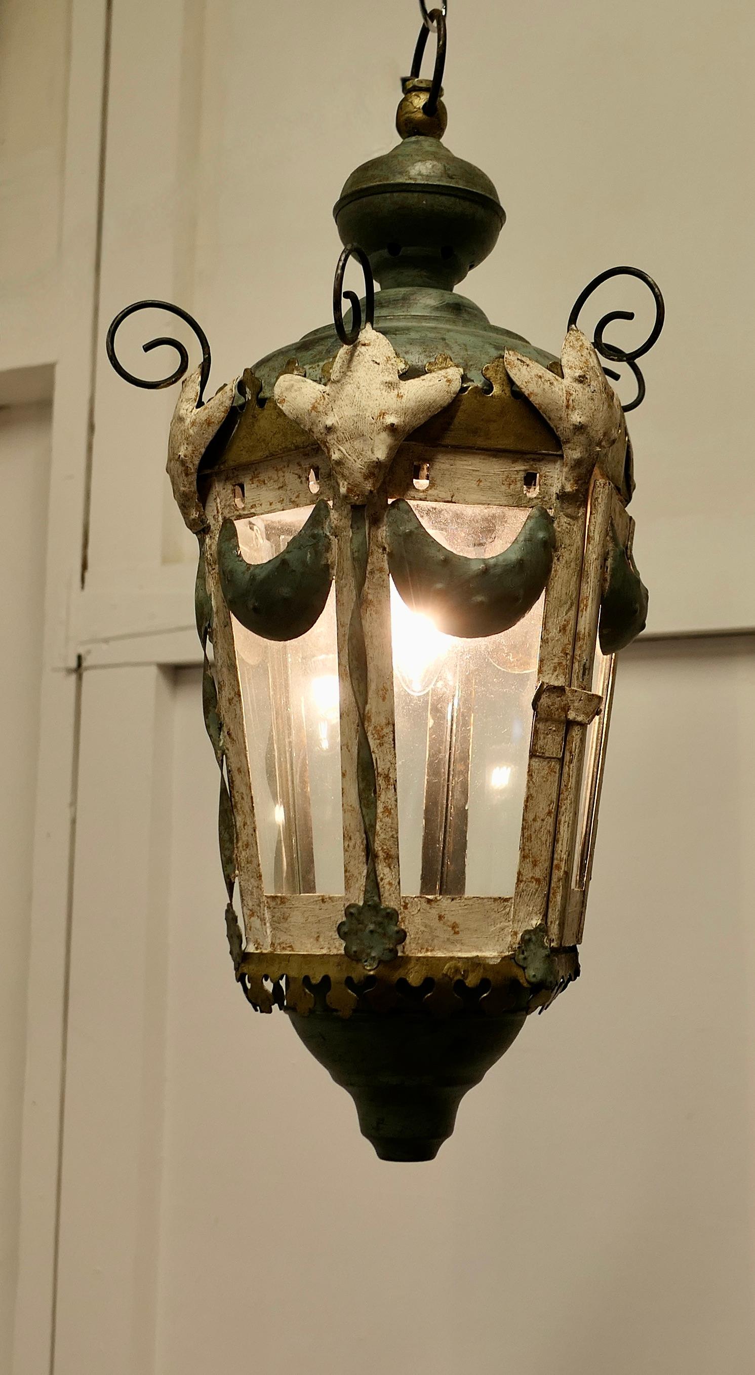 A Very Decorative Italian Tolwear Lantern

This very unusual Hall Lantern is painted to simulate verdigris patination, the Lamp has 6 sides 
(one of these is a locking opening door to access the interior)

This very unusual Baroque light is wired