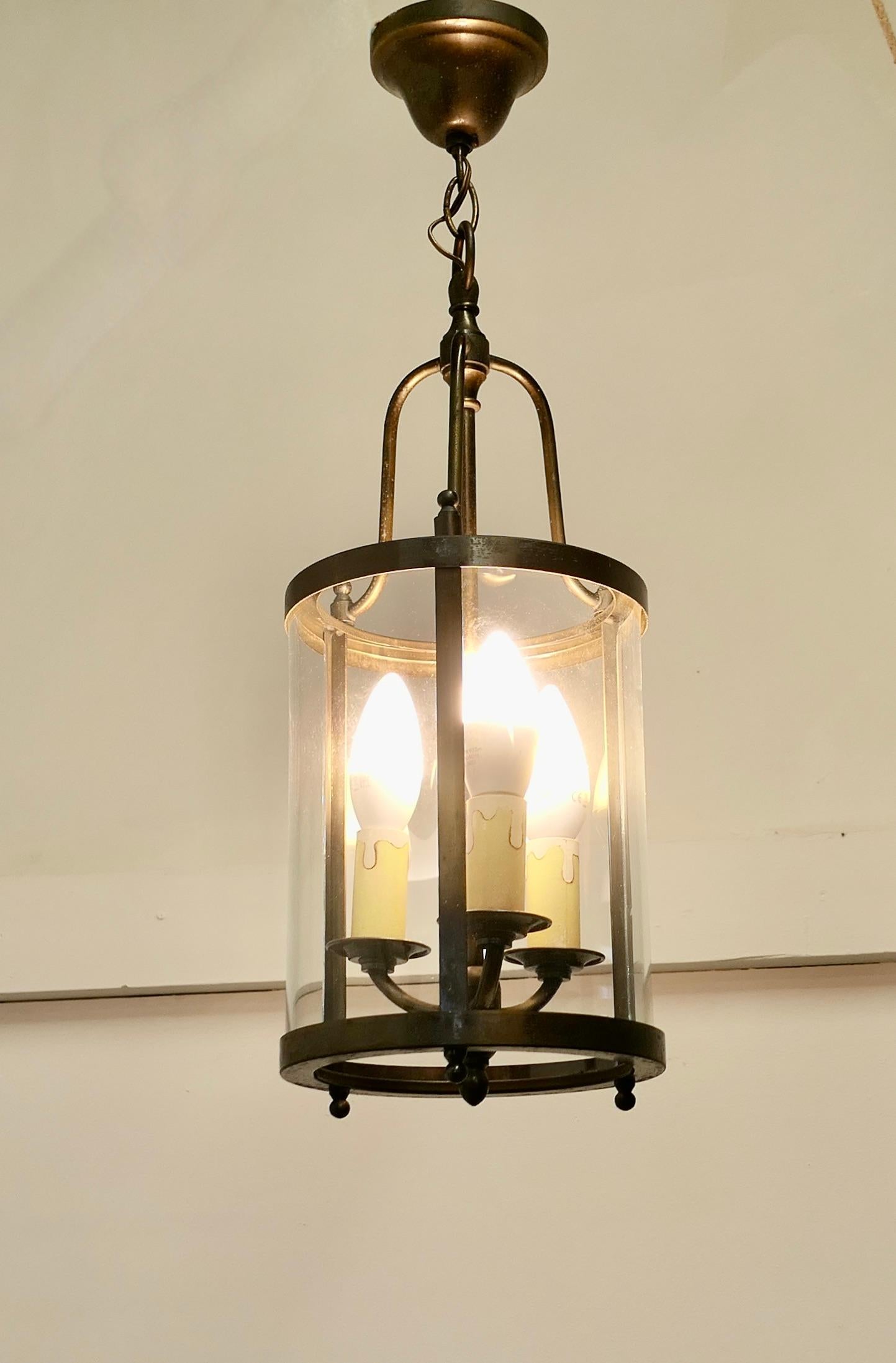 French Art DecoBrass and Glass Lantern Hall Light

A traditional lantern, the light has a cylindrical glass shade, and a triple light fitting to the interior it hangs on a short chain from a brass ceiling rose
The lantern gives a sensational bright