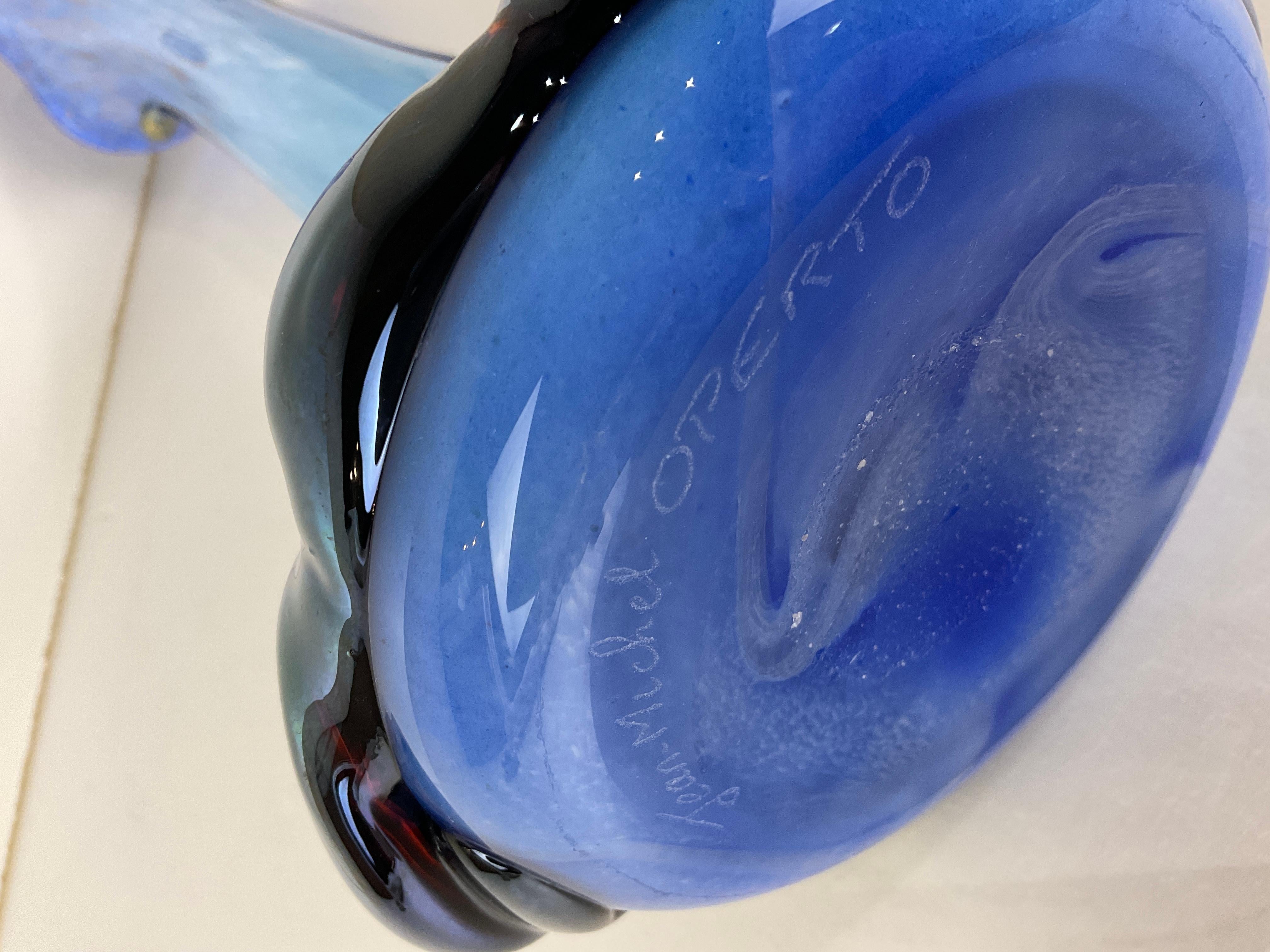 Diese einzigartige und raffinierte Vase im Art-Déco-Stil ist aus mundgeblasenem Glas gefertigt und handdekoriert. Dieses Stück würde jede Umgebung aufwerten. 
Die Kreation besticht durch ihre spitz zulaufende und geschwungene Oberfläche. Die Linien