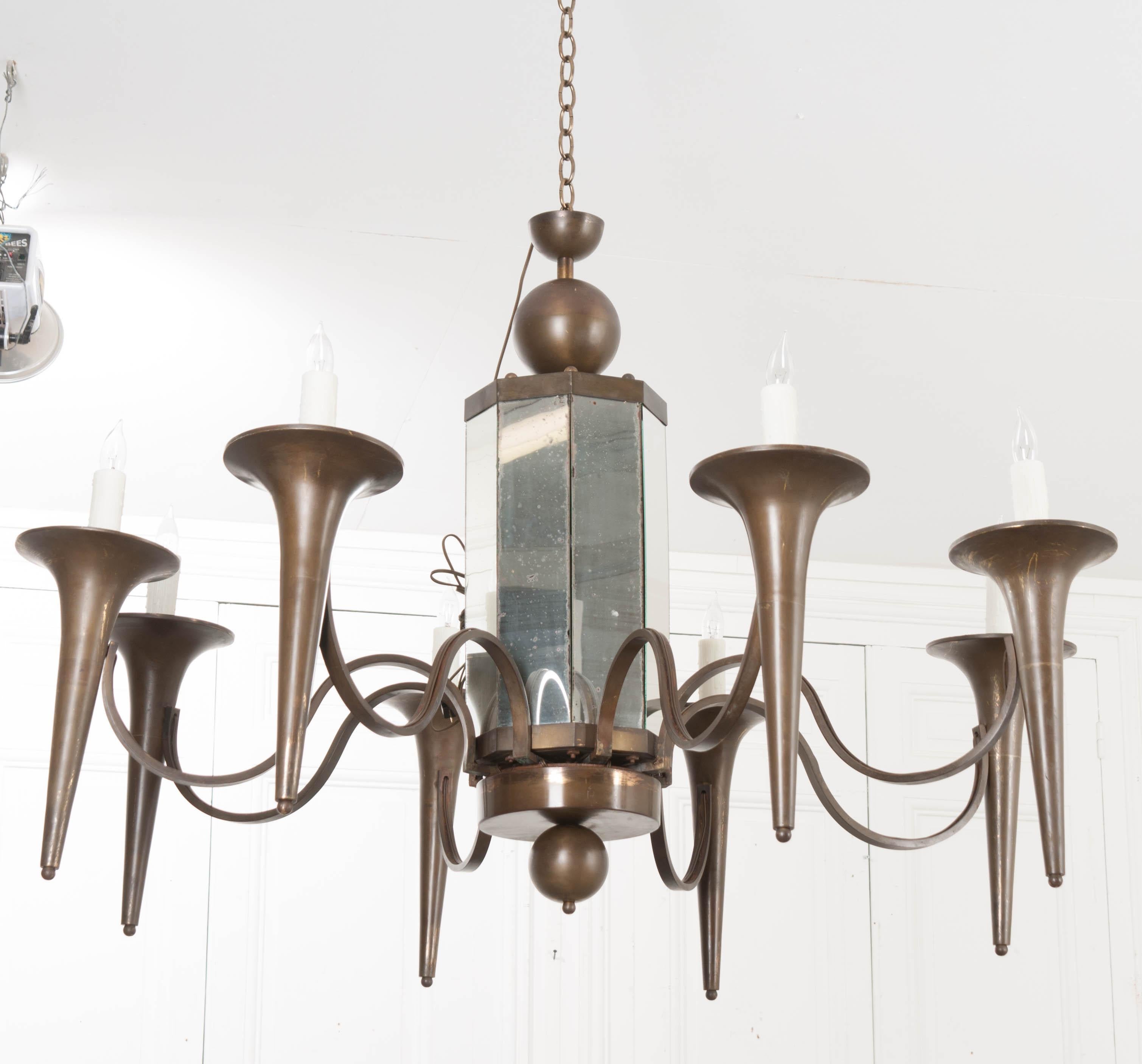 This fabulous, large Art Moderne bronze finished eight-light chandelier, c. 1930s, is from France and features a paneled and mirrored standard, composed of old and new mirror plates, suspending eight scroll-arms terminating with trumpet-form