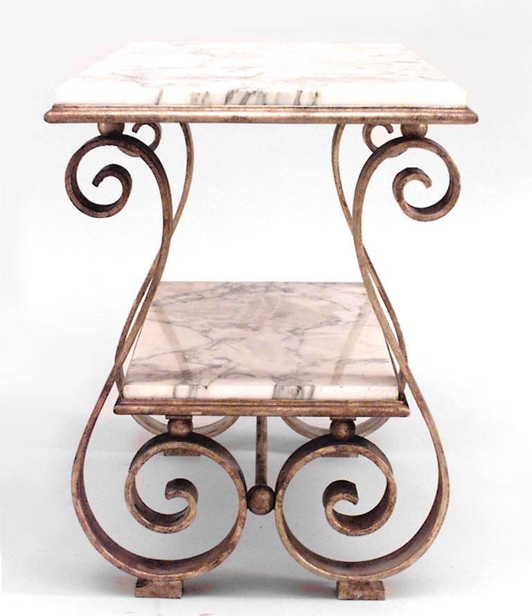 Table basse en fer forgé doré de style Art Moderne français, à plateau rectangulaire en marbre blanc et sous plateau sur pieds en volute en S. (Manière de GILBERT POILLERAT)
