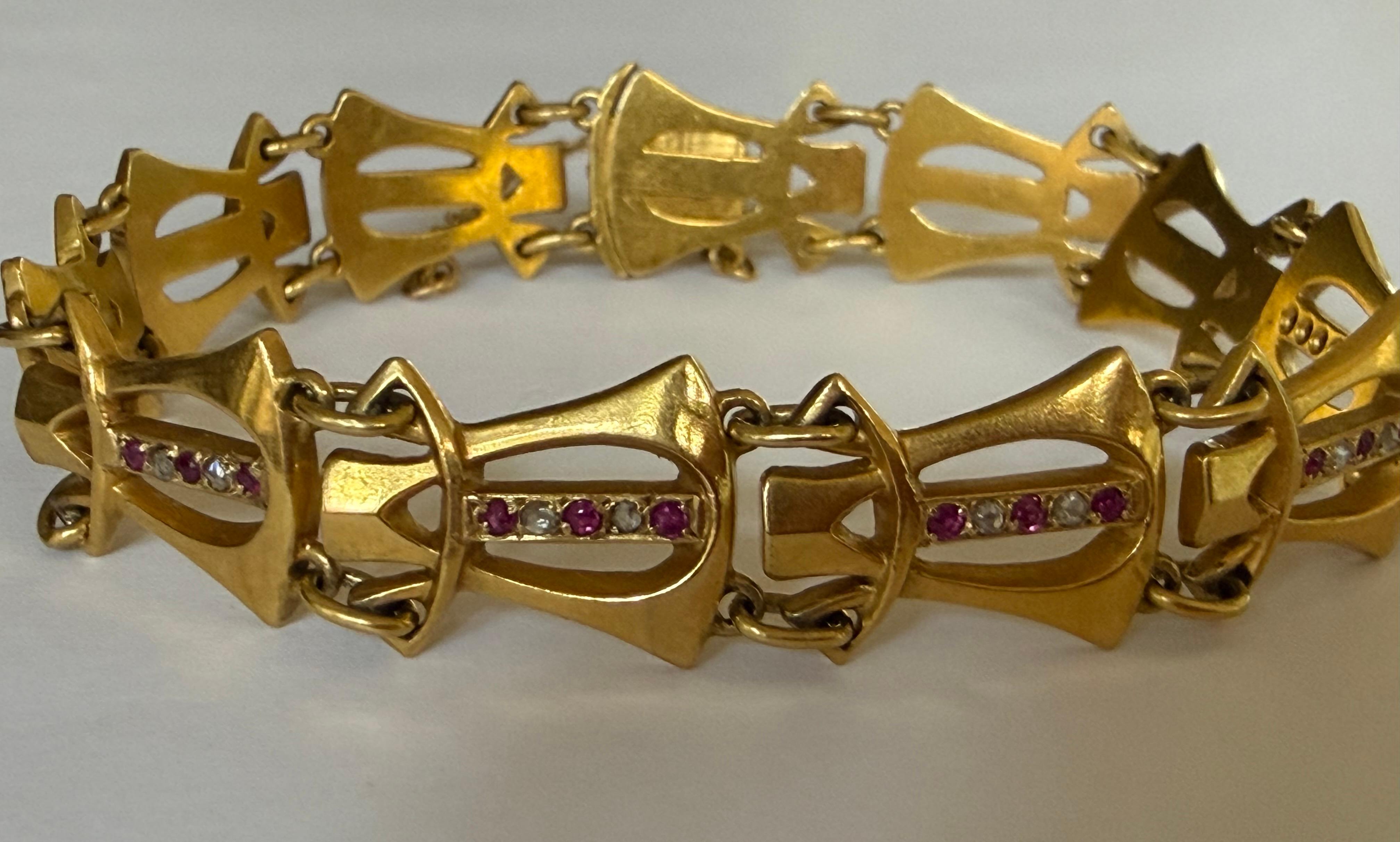 Ce bracelet antique Art Nouveau présente un motif répétitif de maillons stylisés réalisés à la main en or jaune 18 carats et ornés de dix diamants taillés en rose totalisant environ 0,05 carat et de quinze rubis rouges ronds. Vers 1910. Fabriqué en
