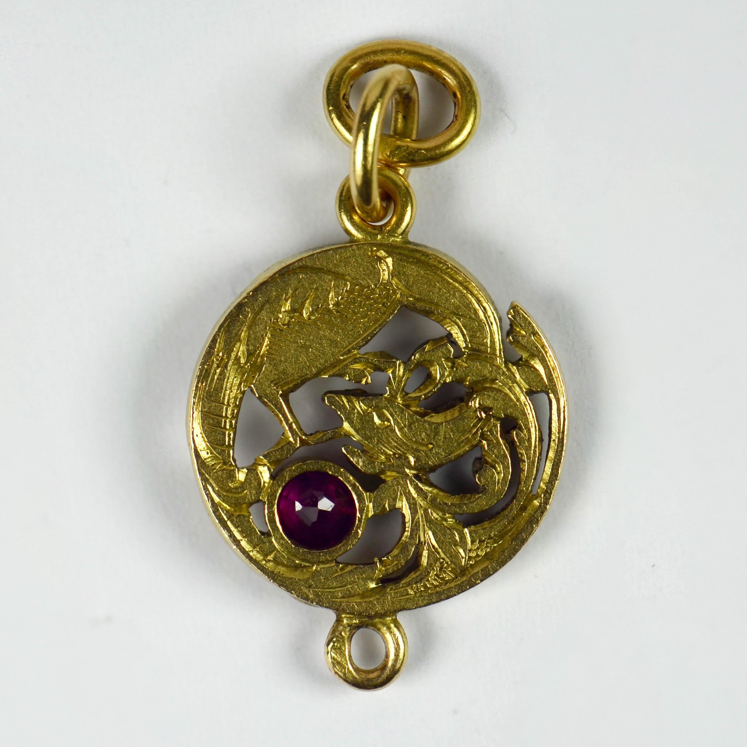 An 18 karat (18K) yellow gold Art Nouveau charm pendant designed as a curled up griffon with a round cut red ruby. The reverse engraved with feathers and lines to further depict this fantastic beast. Stamped with the eagle’s head for 18 karat gold