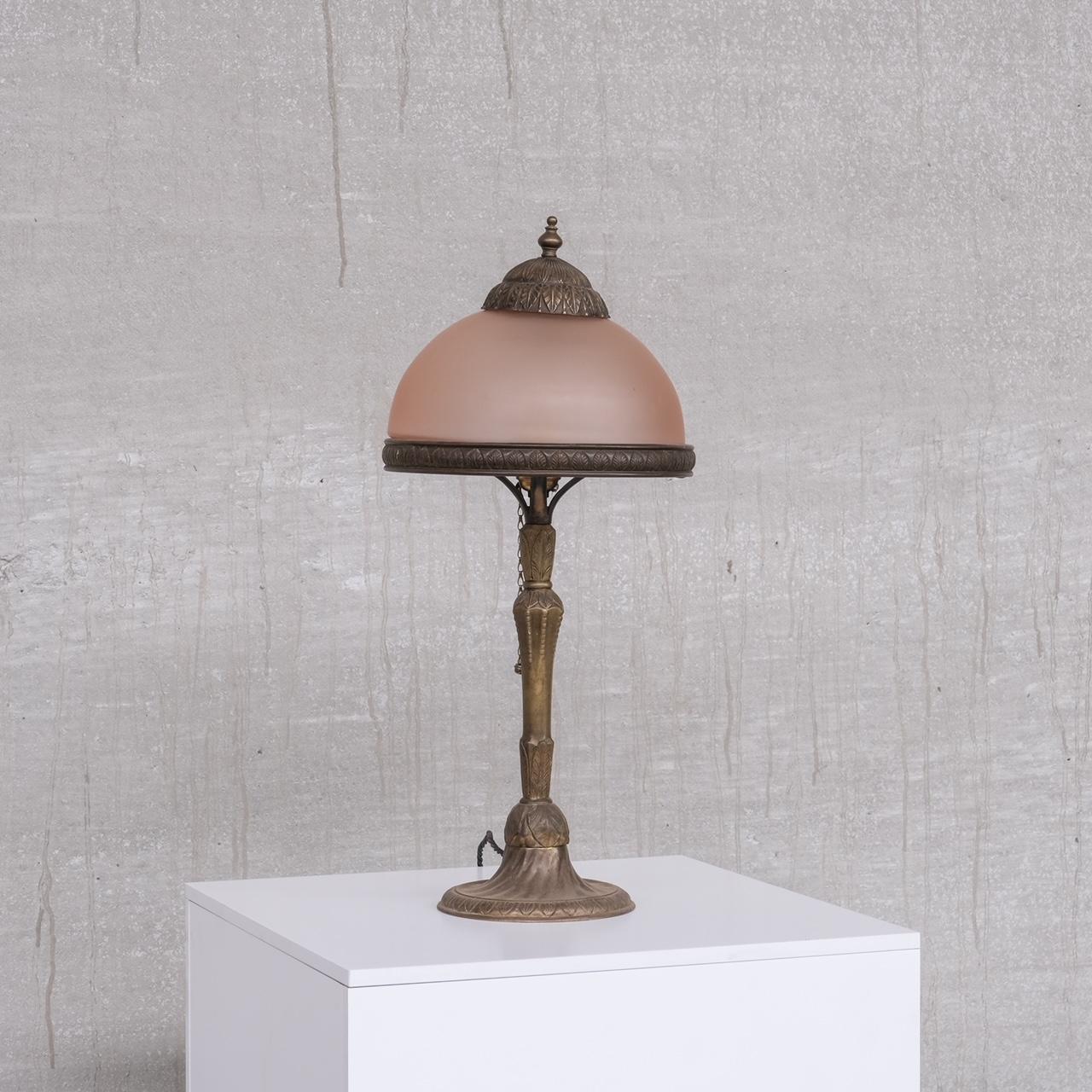 An Art Nouveau brass table lamp, with pink muted glass shade.

France, circa 1910s.

Good quality brass.

Re-wired and PAT tested.

Not a period we usually buy but this piece is particularly pleasing.

Location: Belgium