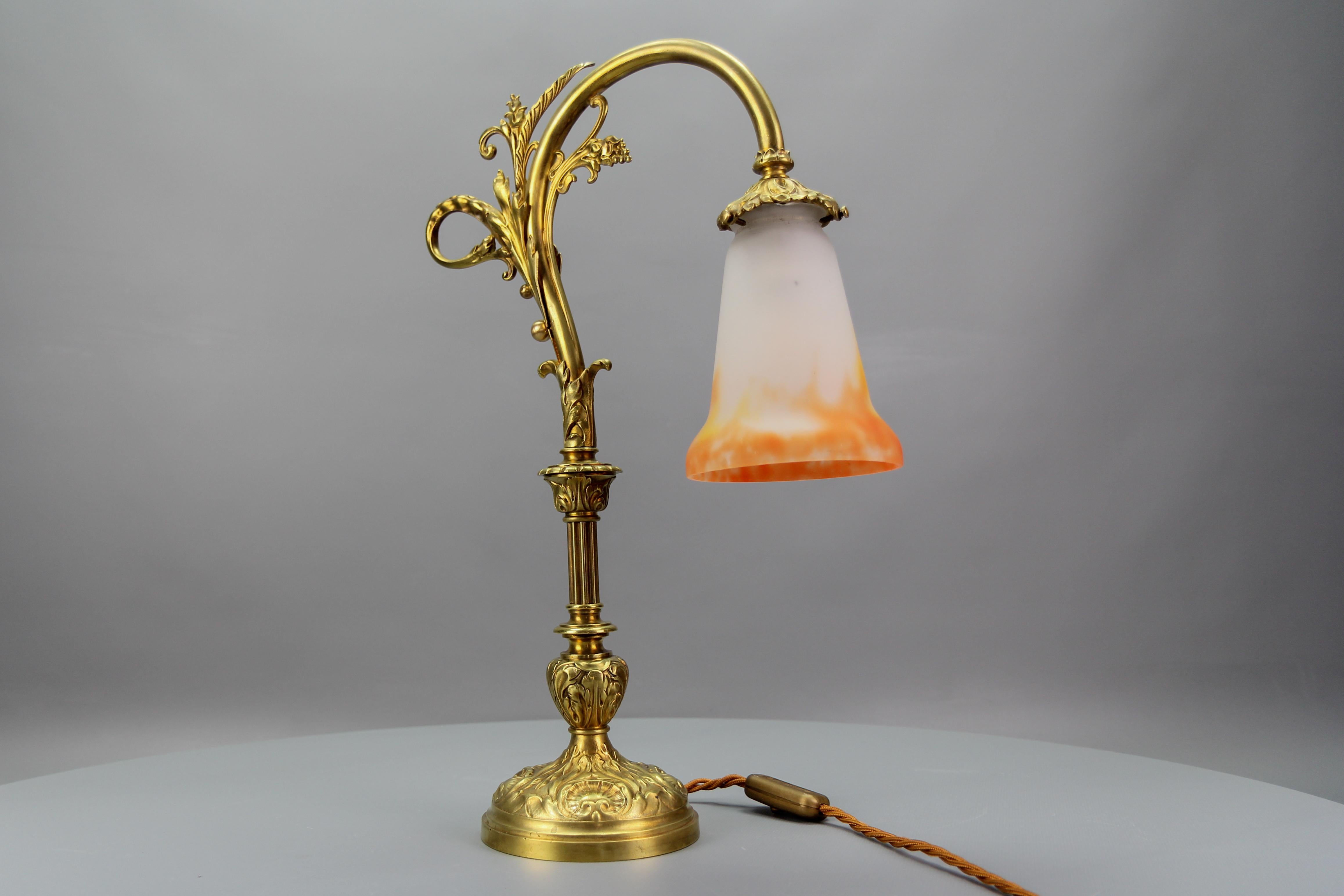 French Art Nouveau bronze table lamp with glass shade signed GV de Croismare, from circa the 1920s.
An adorable and large French bronze table lamp adorned with acanthus leaf scrolls and Rococo shell motifs.
Beautiful glass lampshade by G.V. de