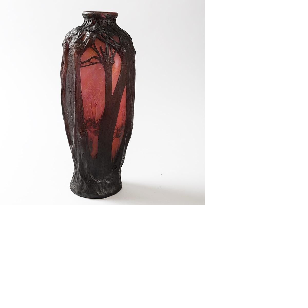 A French 'Paysage, moulage en relief' cameo glass vase by Daum. This vase depicts dark brown tree trunks, roots and branches in relief against a rose colored sky. In the clearings are carved flowers on stems, circa 1910.

A vase with similar motif