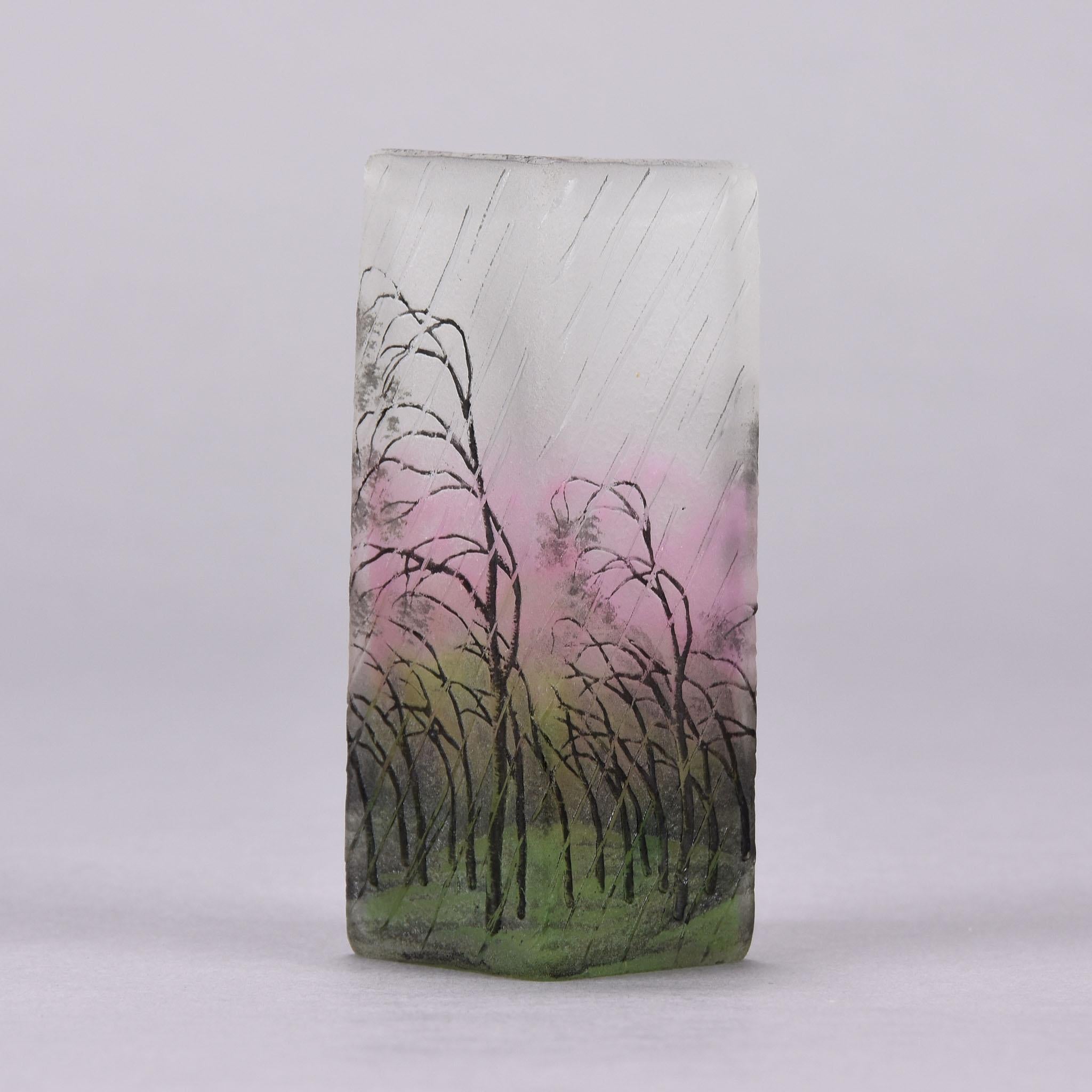 Un merveilleux vase en verre camée gravé et émaillé de bouleaux argentés courbés dans un paysage balayé par la pluie. Le design est rehaussé de couleurs rose et vertes profondes entrelacées à la surface pour donner une profondeur de champ