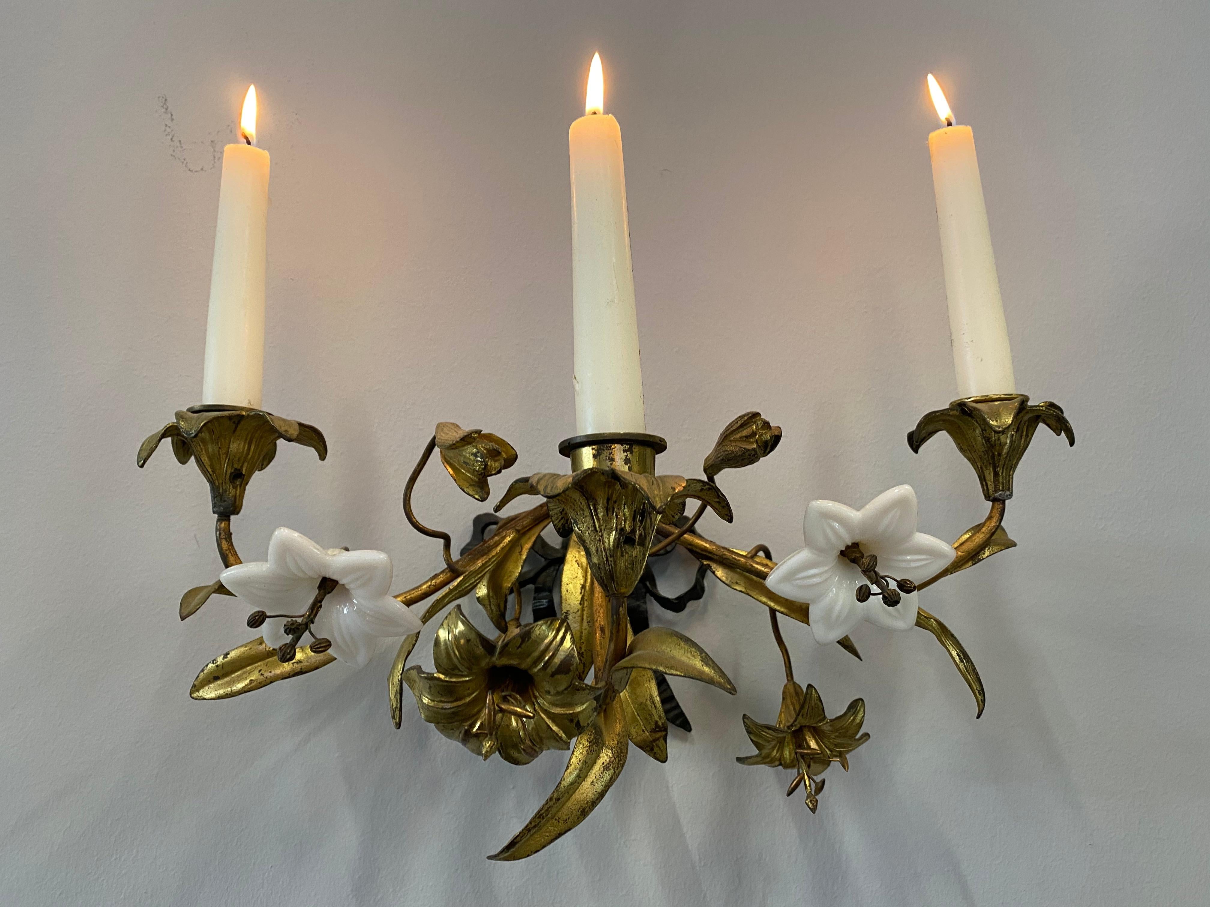This playful Art Nouveau wall candleholder is a unique wall decoration. The candleholder has three arms which are surrounded by gilded metal and glass flowers and leaves. The holder on the wall forms a loop. Equipped with 3 candles the candleholder
