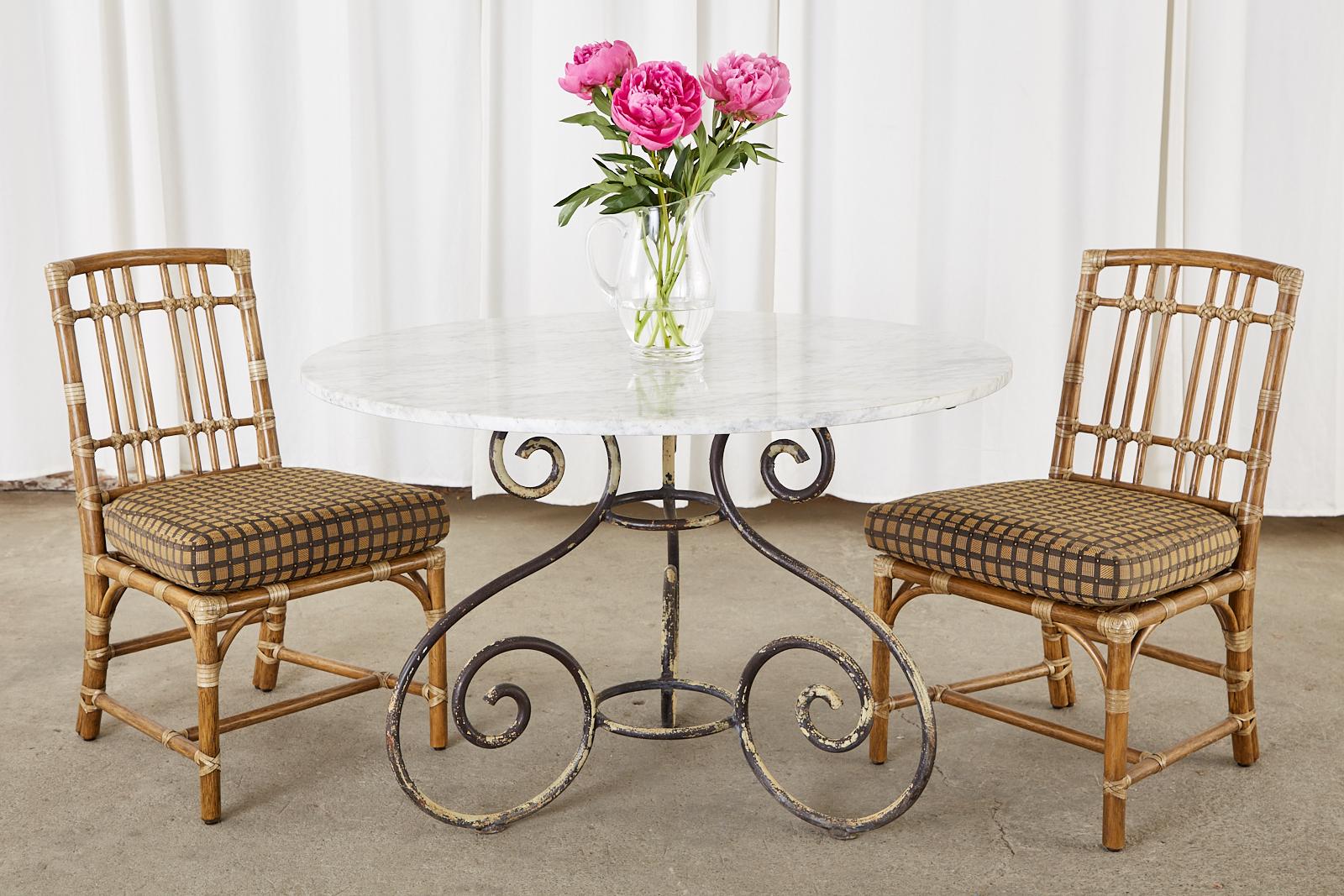 Extraordinary French art nouveau garden dining table or centre table featuring a 1 inch thick round Carrara marble top. The top is supported by a three leg iron base conjoined in the middle with ring stretchers. The legs are crafted from solid iron