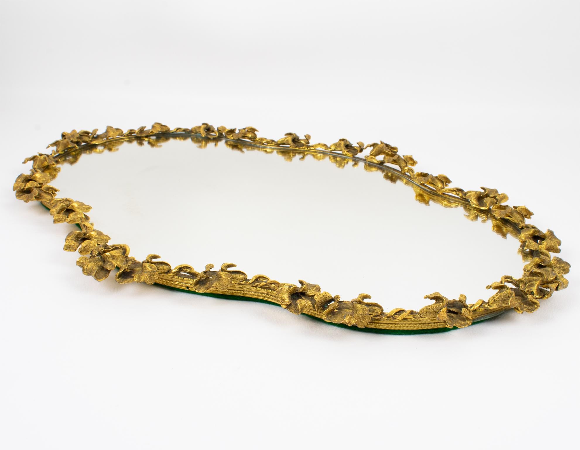Esta adorable bandeja grande o centro de mesa Art Nouveau se fabricó a mano en Francia hacia 1910. La impresionante fuente tiene un marco ovalado de bronce dorado con finos detalles y está ornamentada con guirnaldas dimensionales de flores de iris.