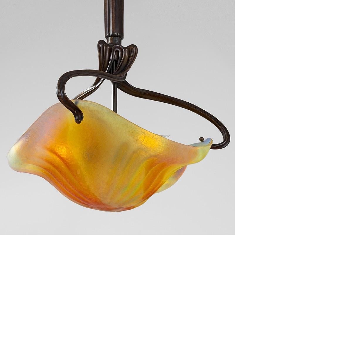 This uniquely-shaped French Art Nouveau chandelier, a collaboration by Louis Majorelle and Daum Nancy, features a glass shade—executed by Daum Nancy—has an abstractly floral, undulating design, rendered subtly in flowing autumnal colors of yellow,