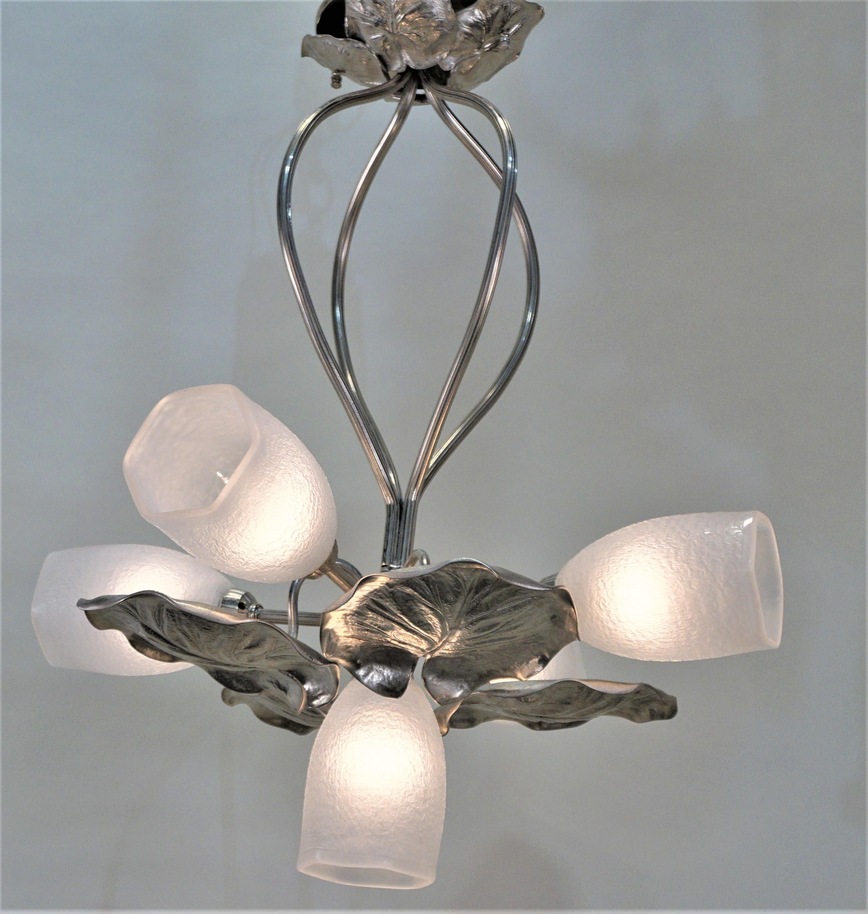 This French 1910s-1920s Art Nouveau chandelier is made of beautiful nickel on bronze and glass.
Four large nickel on bronze leaves hang from the center, and five shaped glass shades extend outwards, creating a naturally inspired design.
This