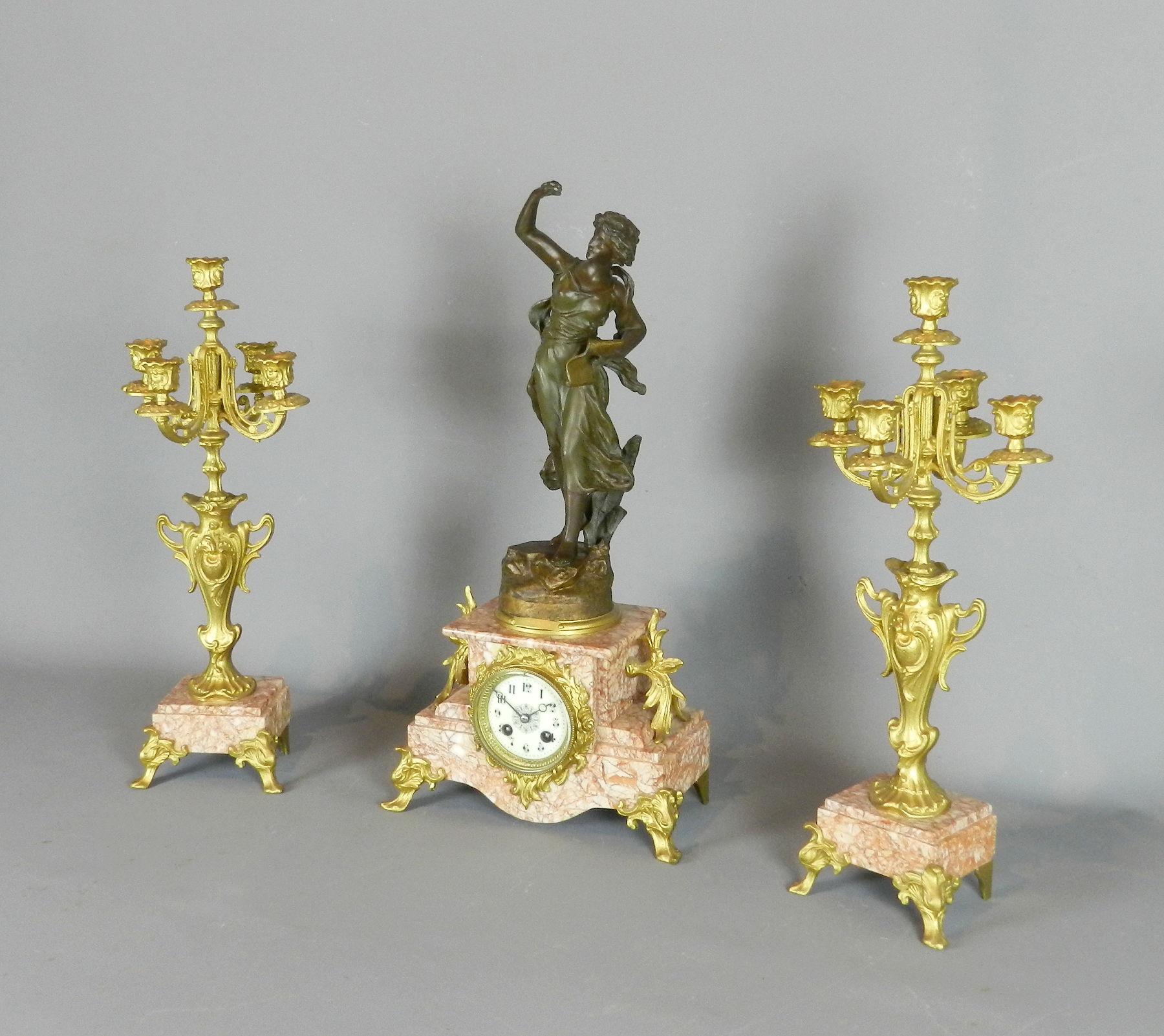 An antique French bronzed spelter clock set with its pair of matching gilt candelabra / garniture. 

The finely cast figurine of a lady holding a manuscript is entitled Poésie and is signed by the maker Jean Charles Ruchot working in the Art